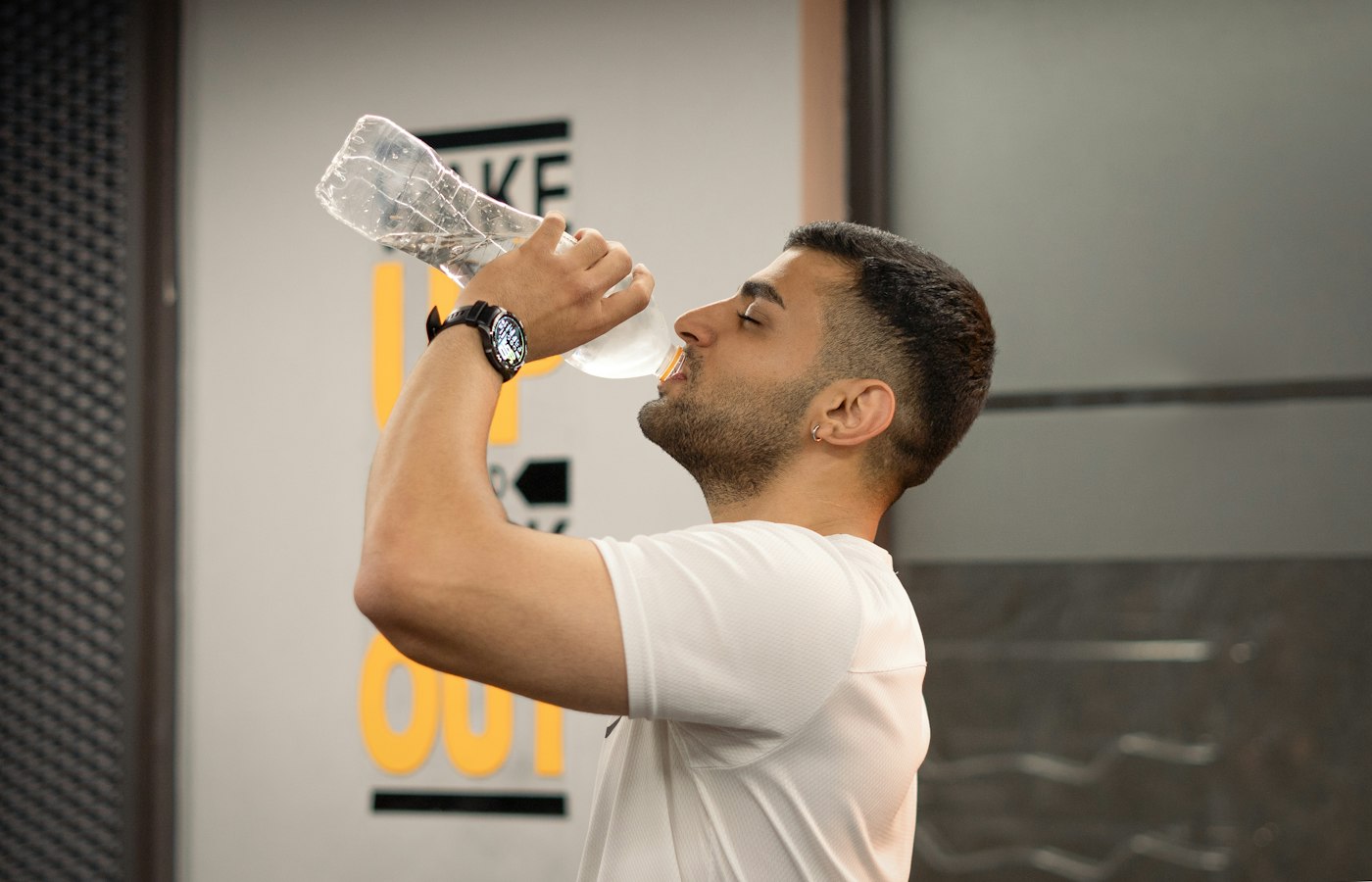 ジムでボトルの水を飲む男性のイメージ写真