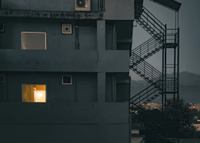 Dark building exterior with illuminated windows and dark windows.