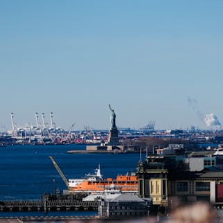 Statue of liberty with new york harbor and industrial background