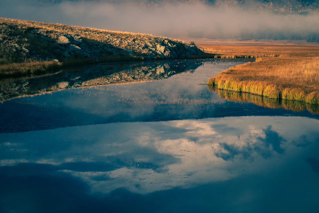 Calm river reflecting clouds and autumn landscape