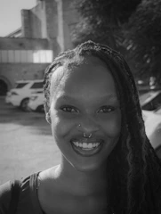 A smiling black woman with braided hair and nose piercings.
