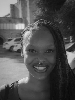 A smiling black woman with braided hair and nose piercings.