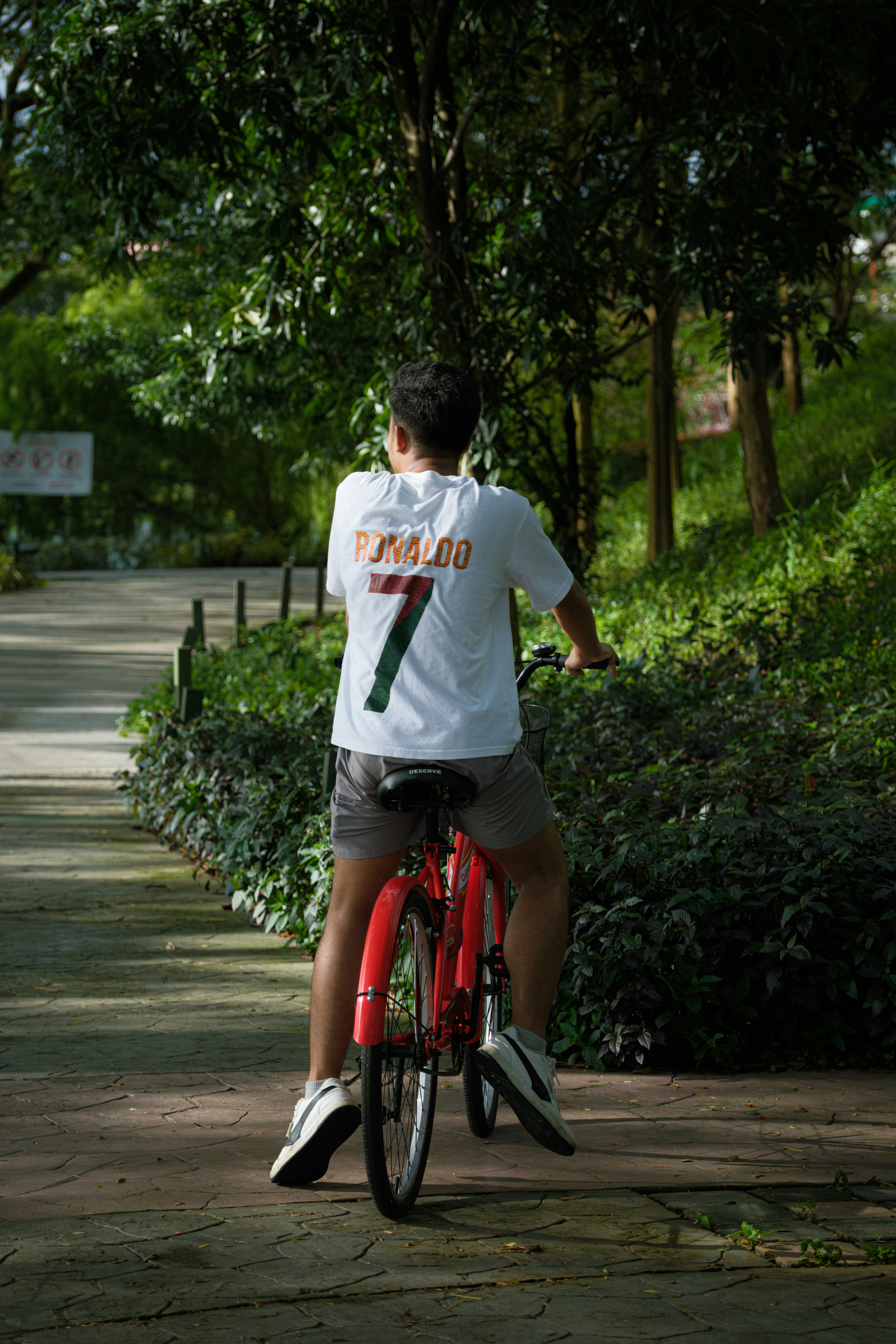 Man riding a red bicycle on a park path.