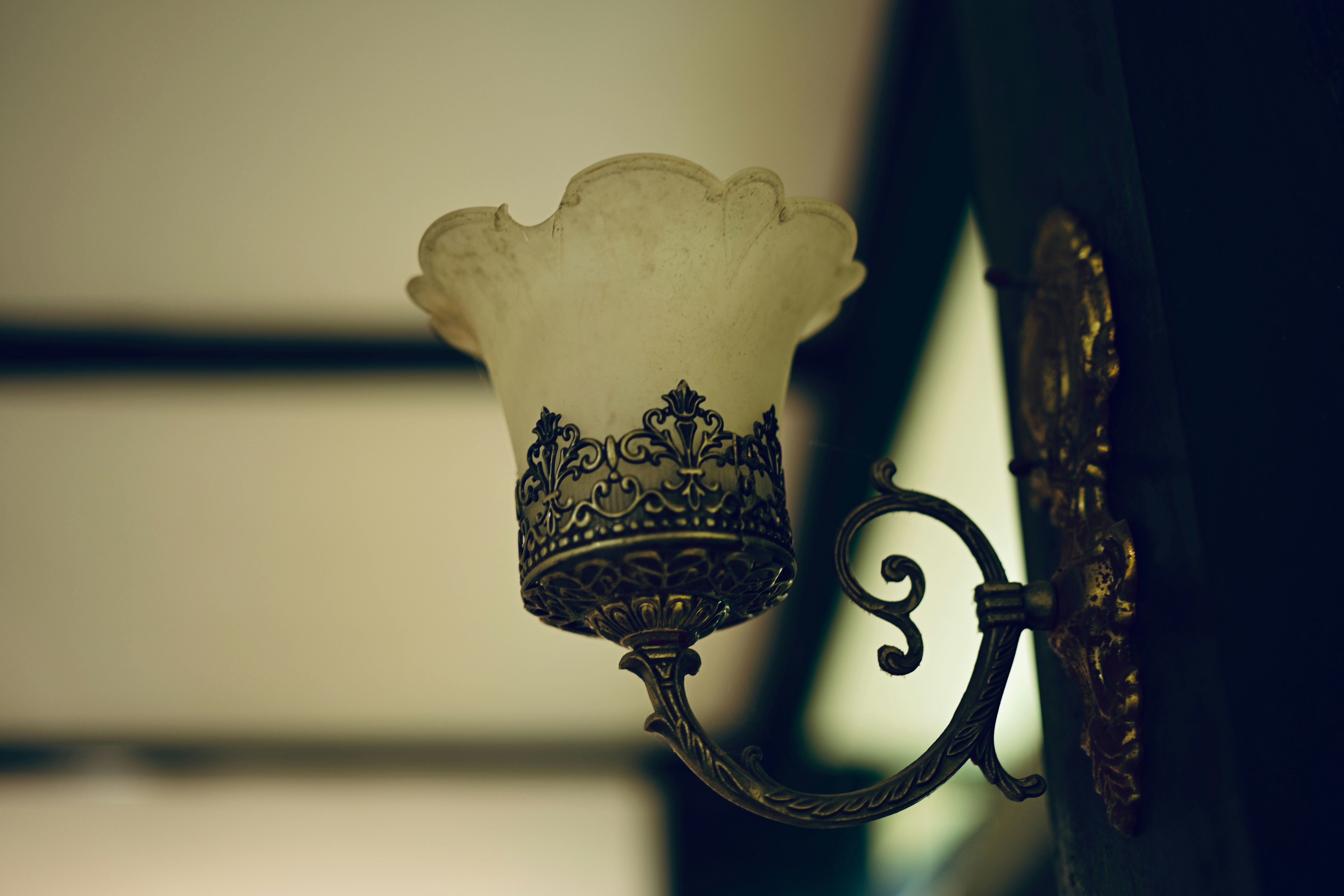 An ornate vintage wall sconce with a glass shade.