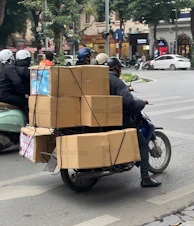 Motorcycle carrying large cardboard boxes on city street