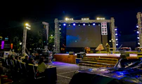 Outdoor stage setup with screen and audience at night