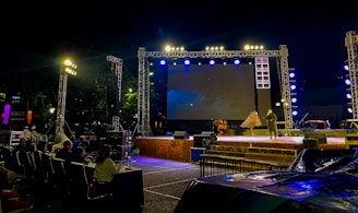 Outdoor stage setup with screen and audience at night