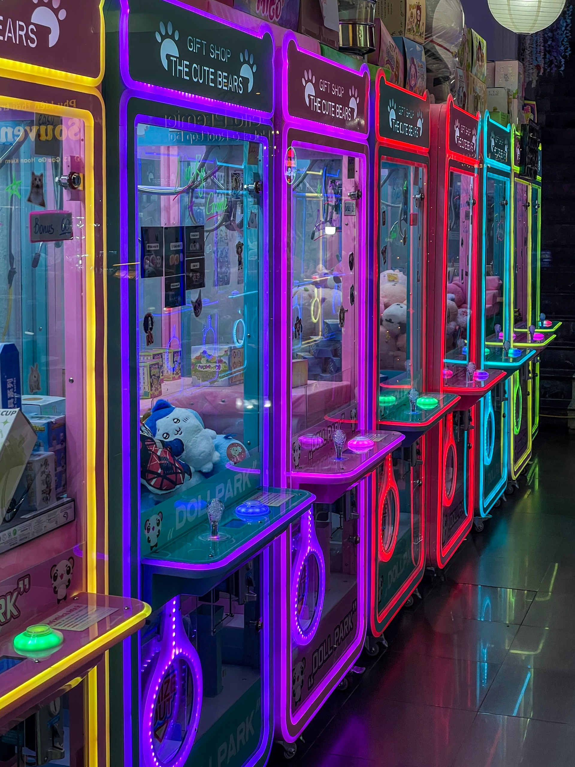 Row of colorful arcade claw machines with prizes