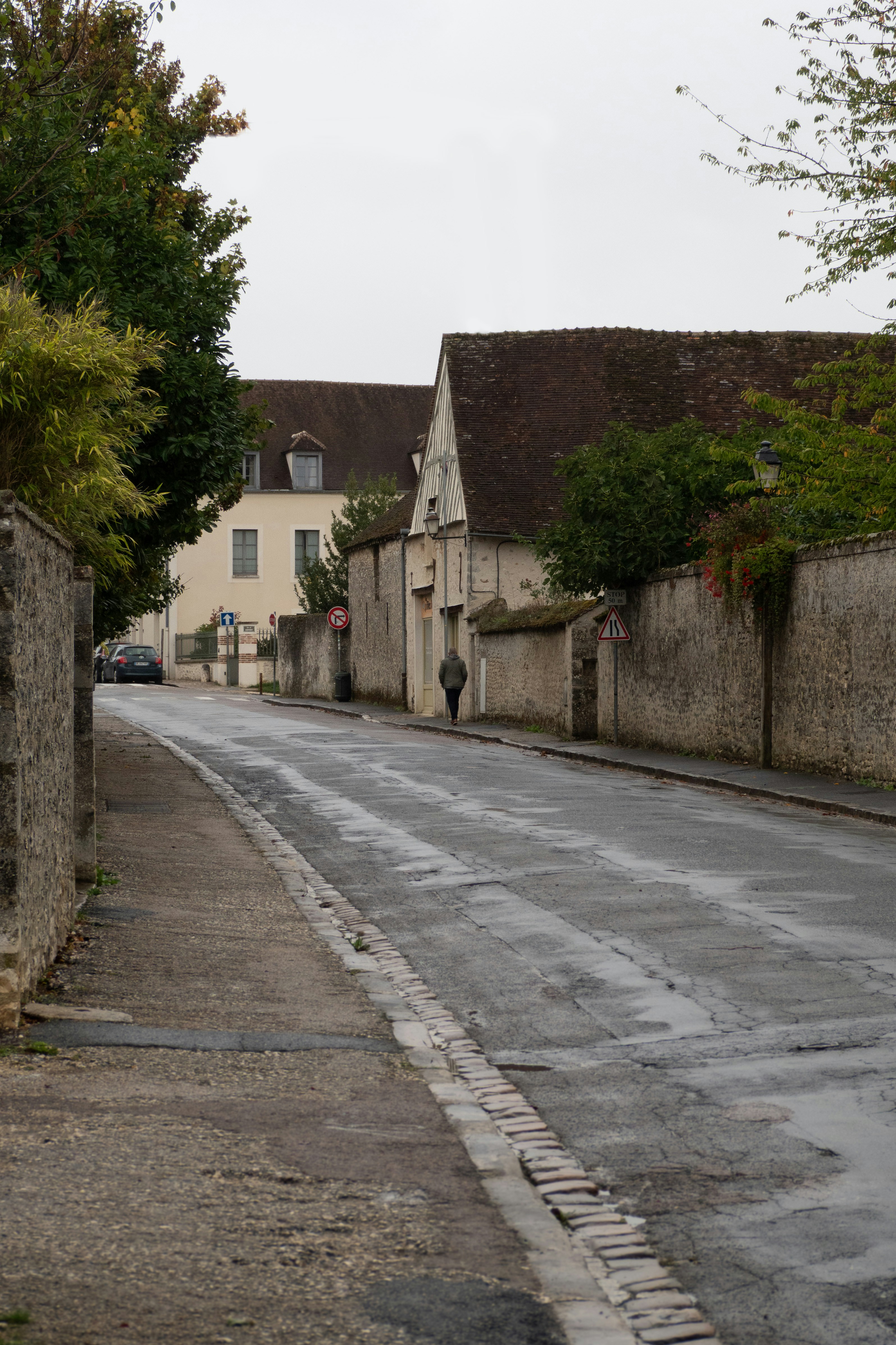 A wet street lined with stone walls and buildings.