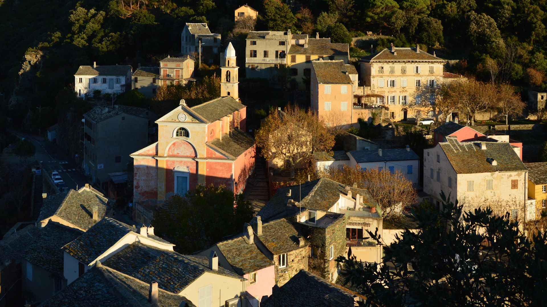 A village nestled in a hillside with trees.