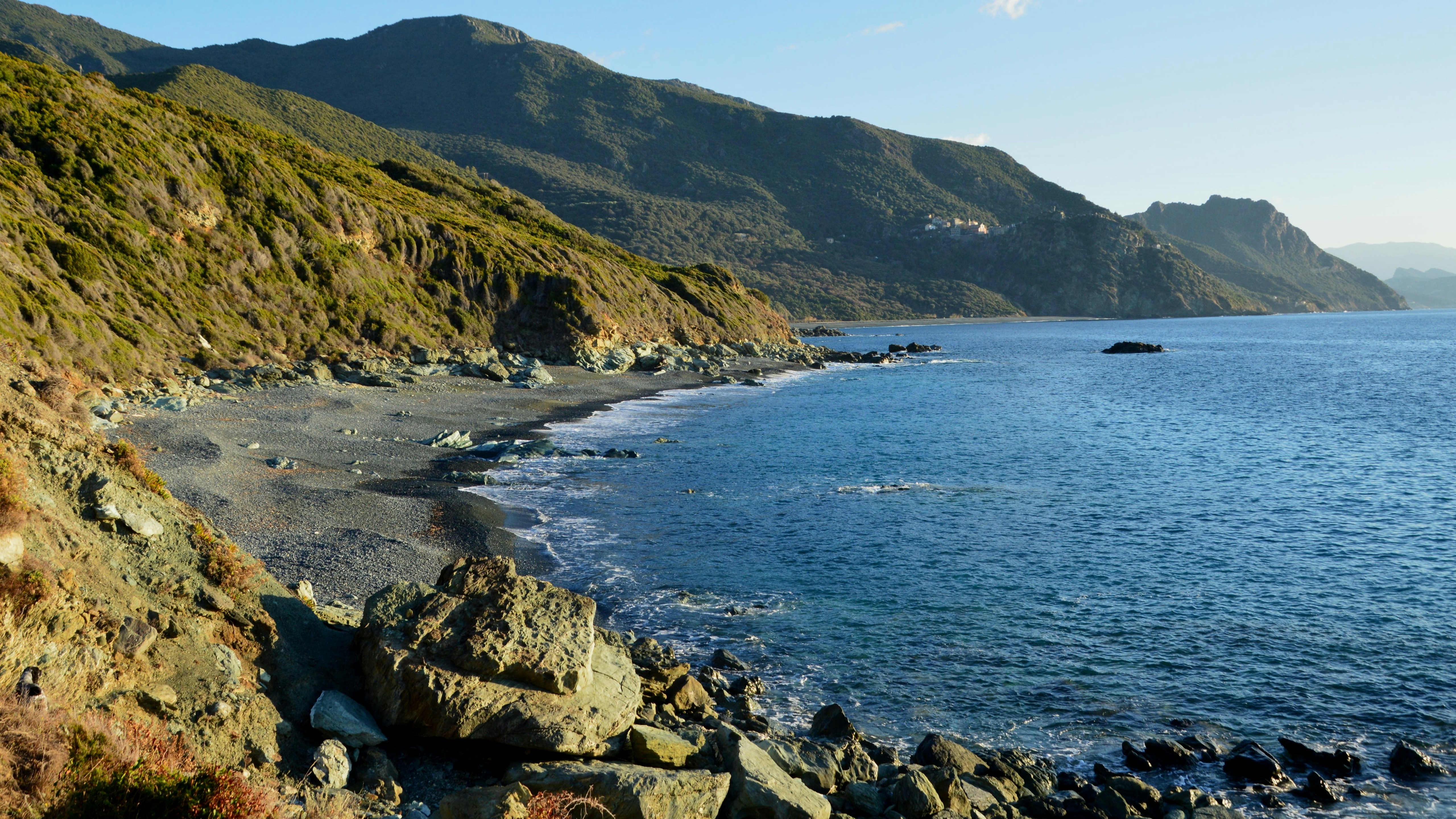 Rocky Mediterranean coastline with blue ocean and green hills