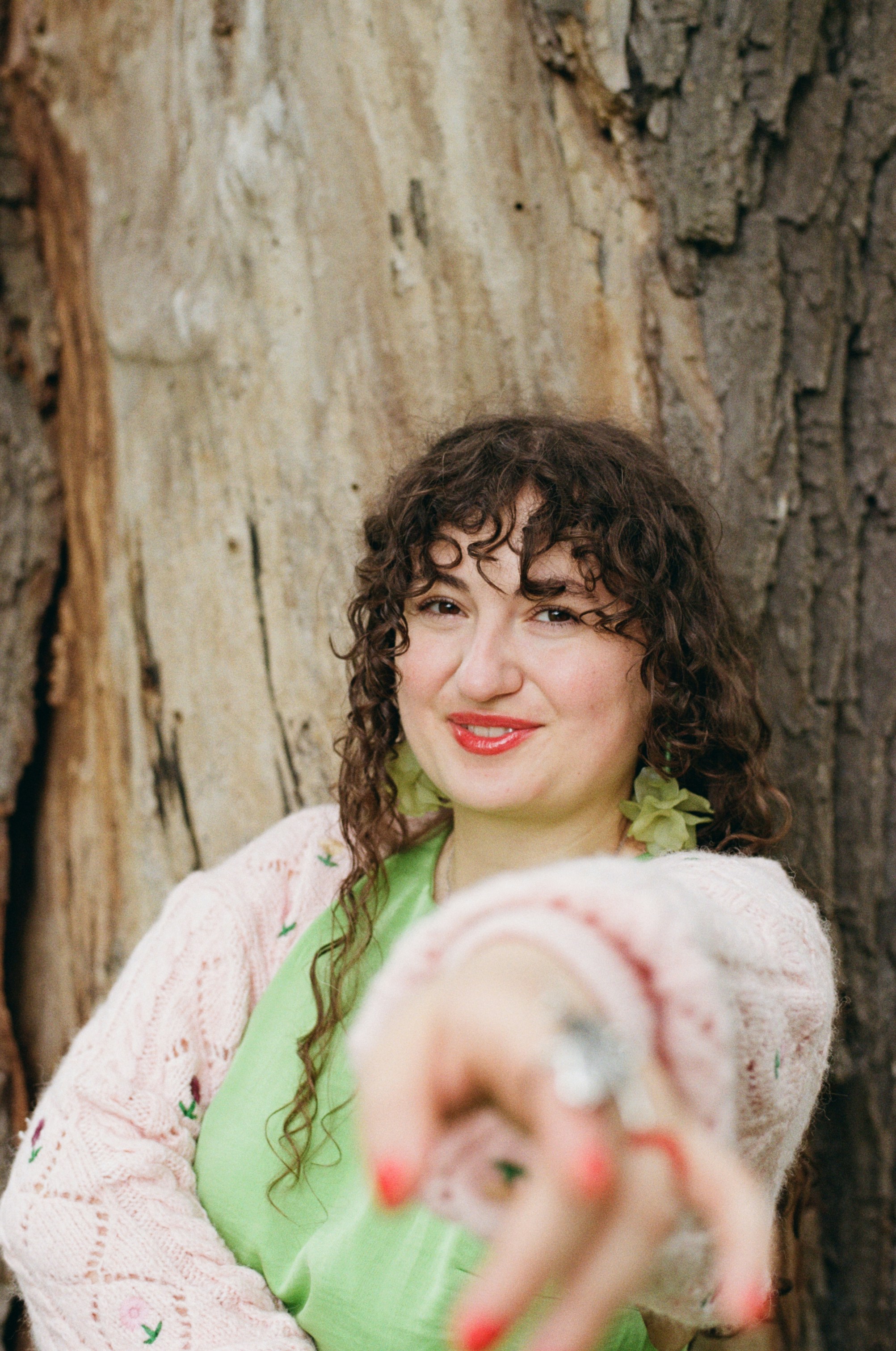 Woman with curly hair reaching towards camera