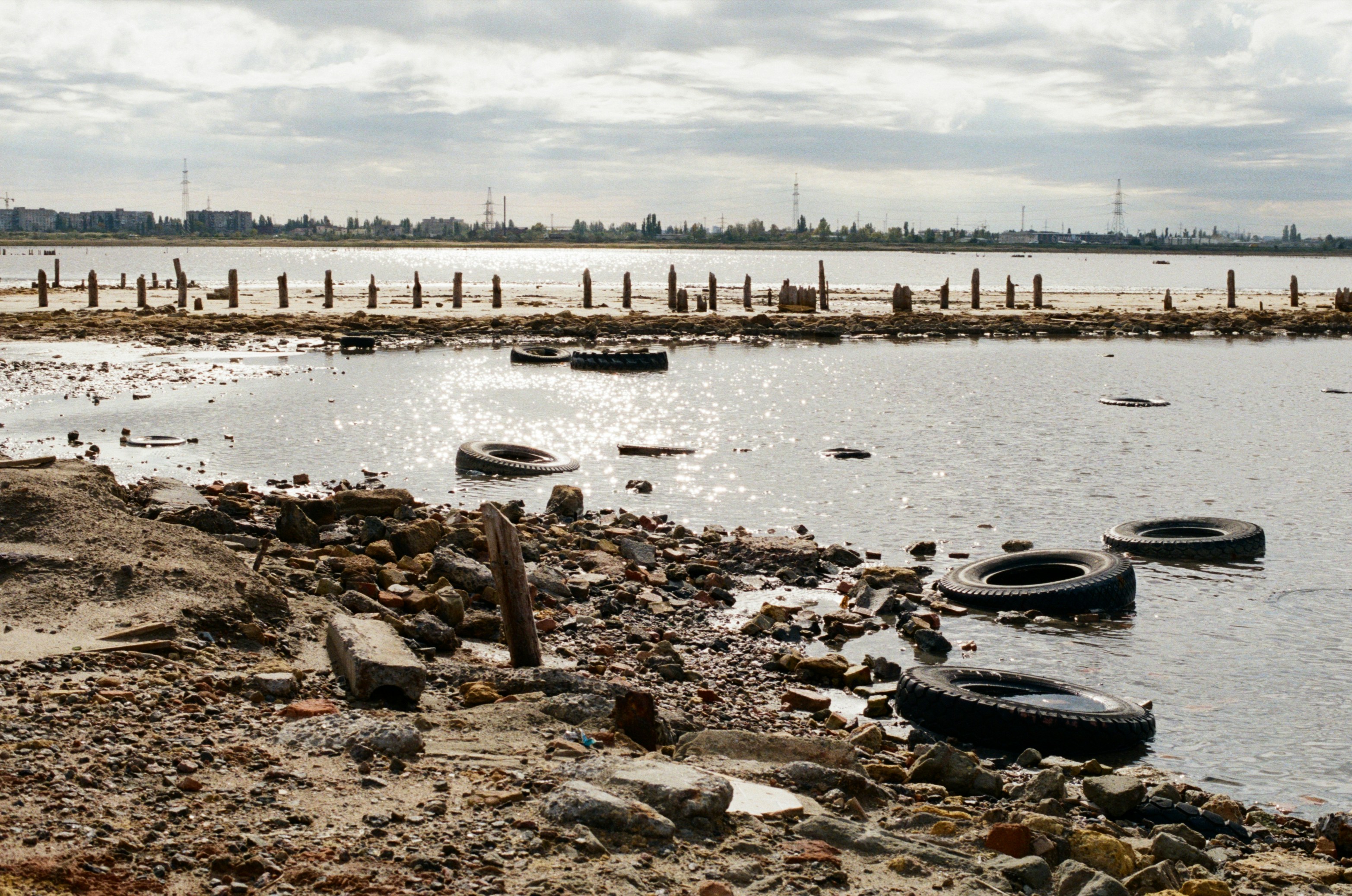 Discarded tires and debris on a polluted shoreline.
