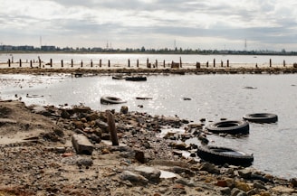 Discarded tires and debris on a polluted shoreline.