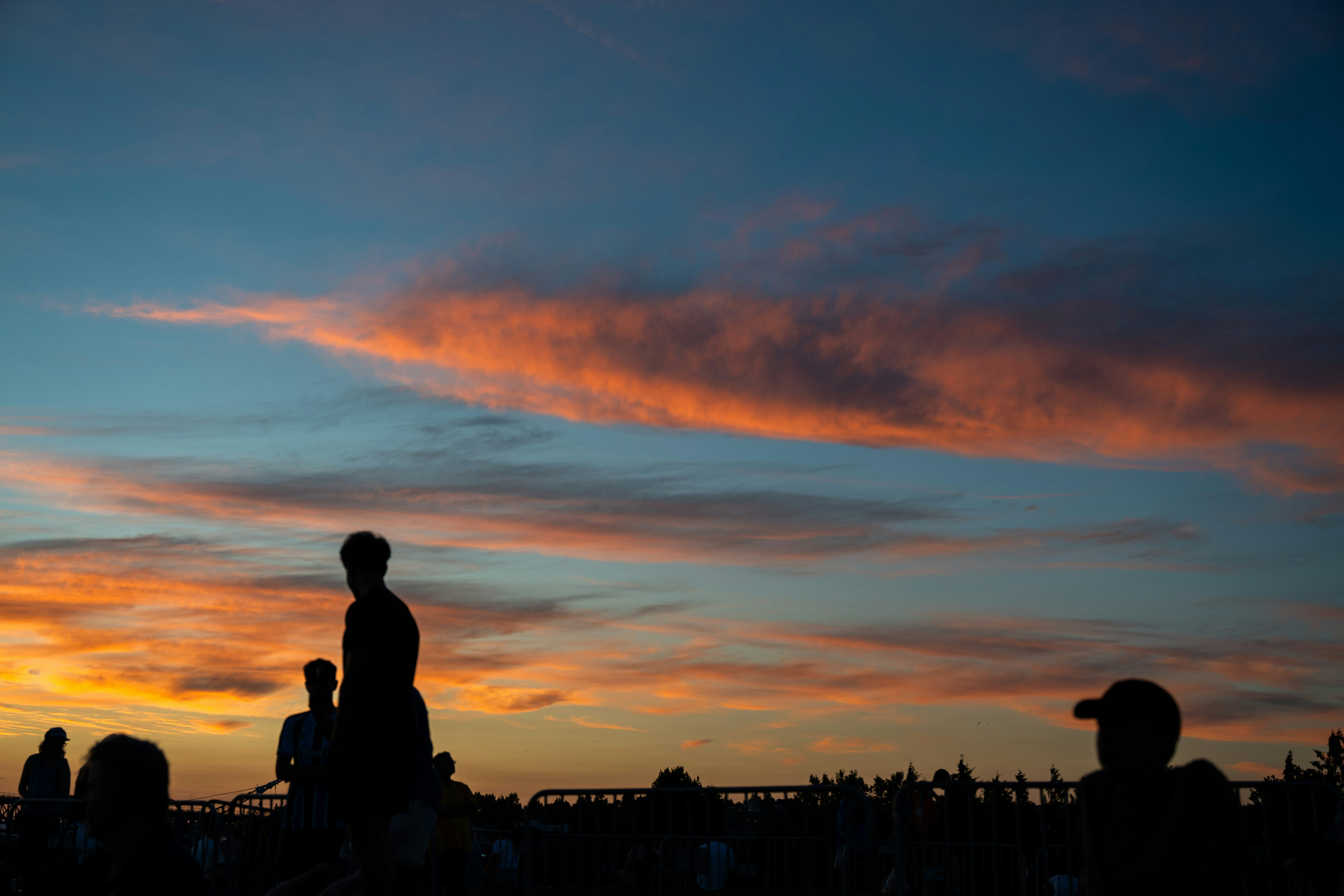 Silhouettes of people watching a vibrant sunset sky