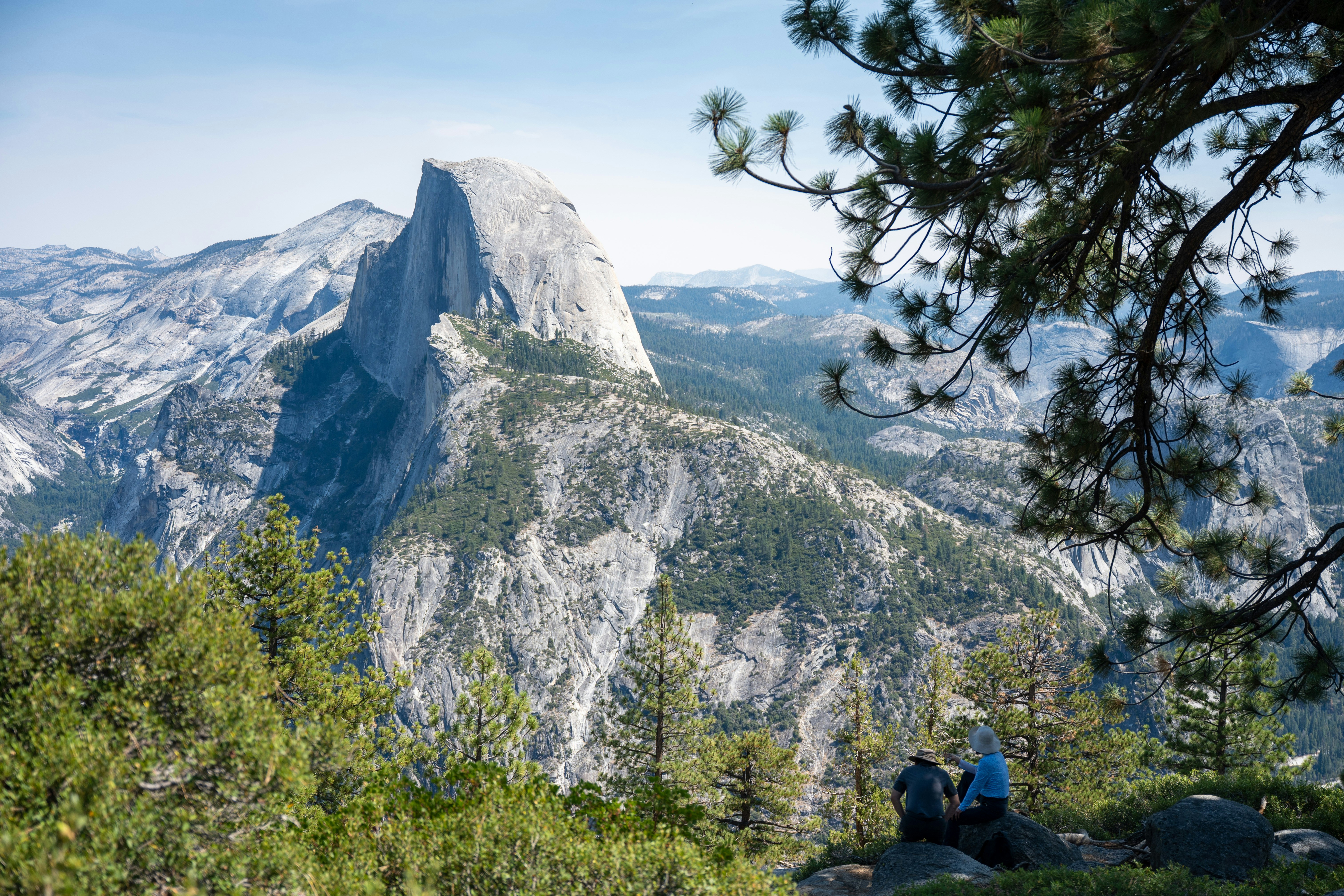Two hikers admire half dome mountain in yosemite national park.