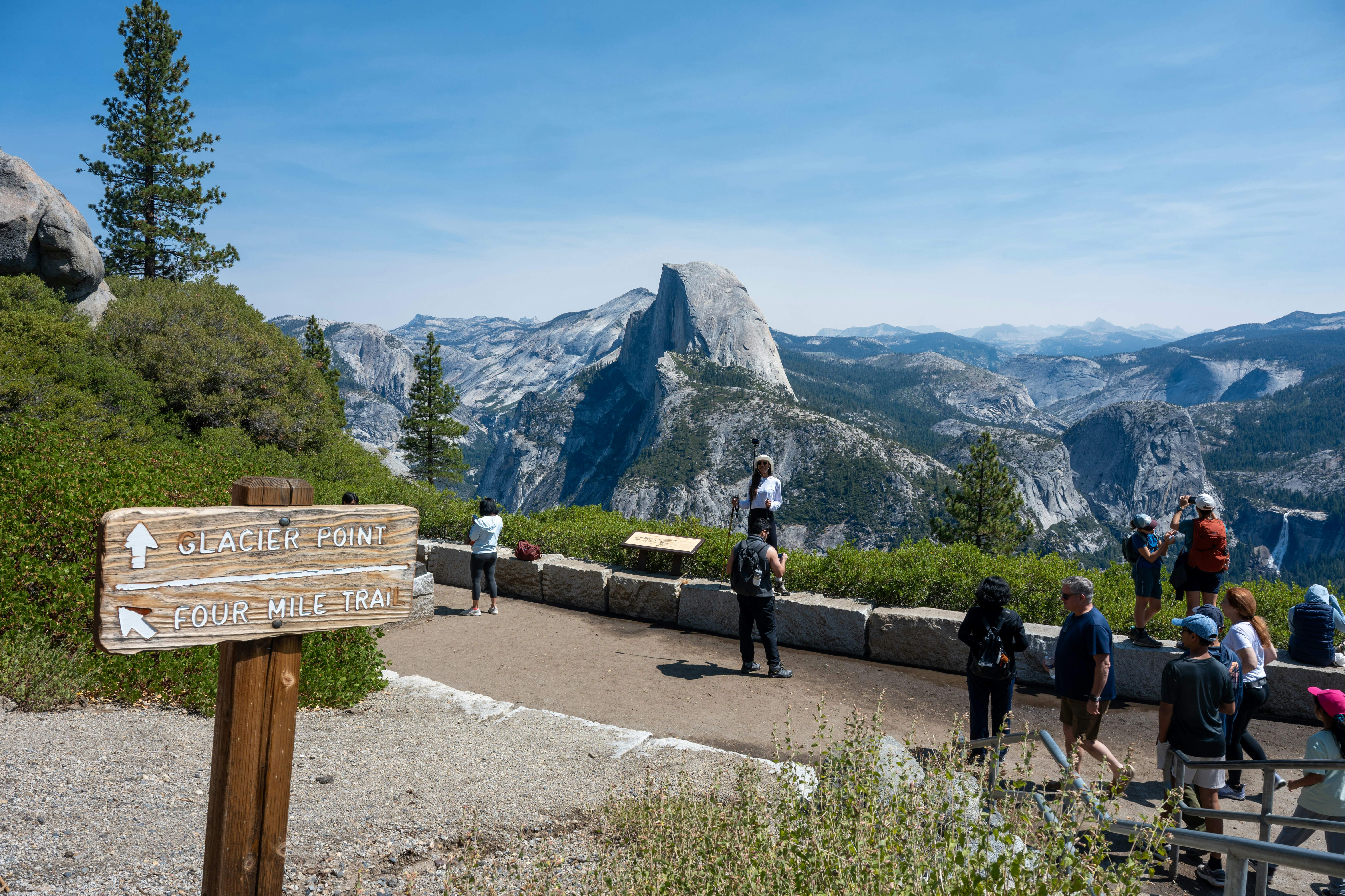 People admire half dome from a scenic viewpoint.