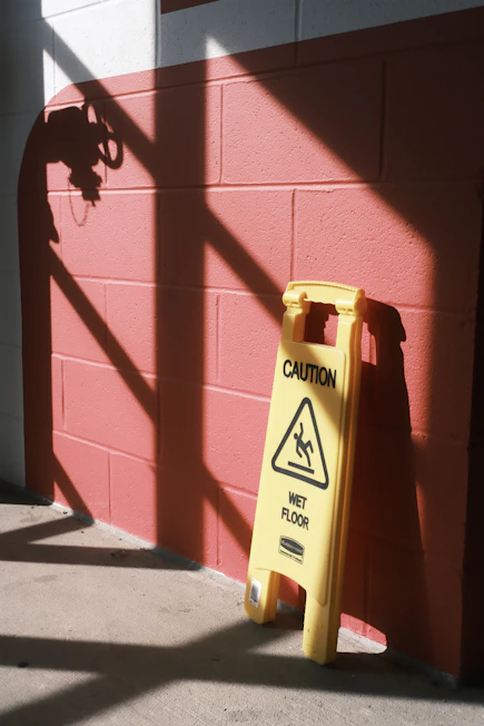Yellow caution sign for wet floor on pink wall
