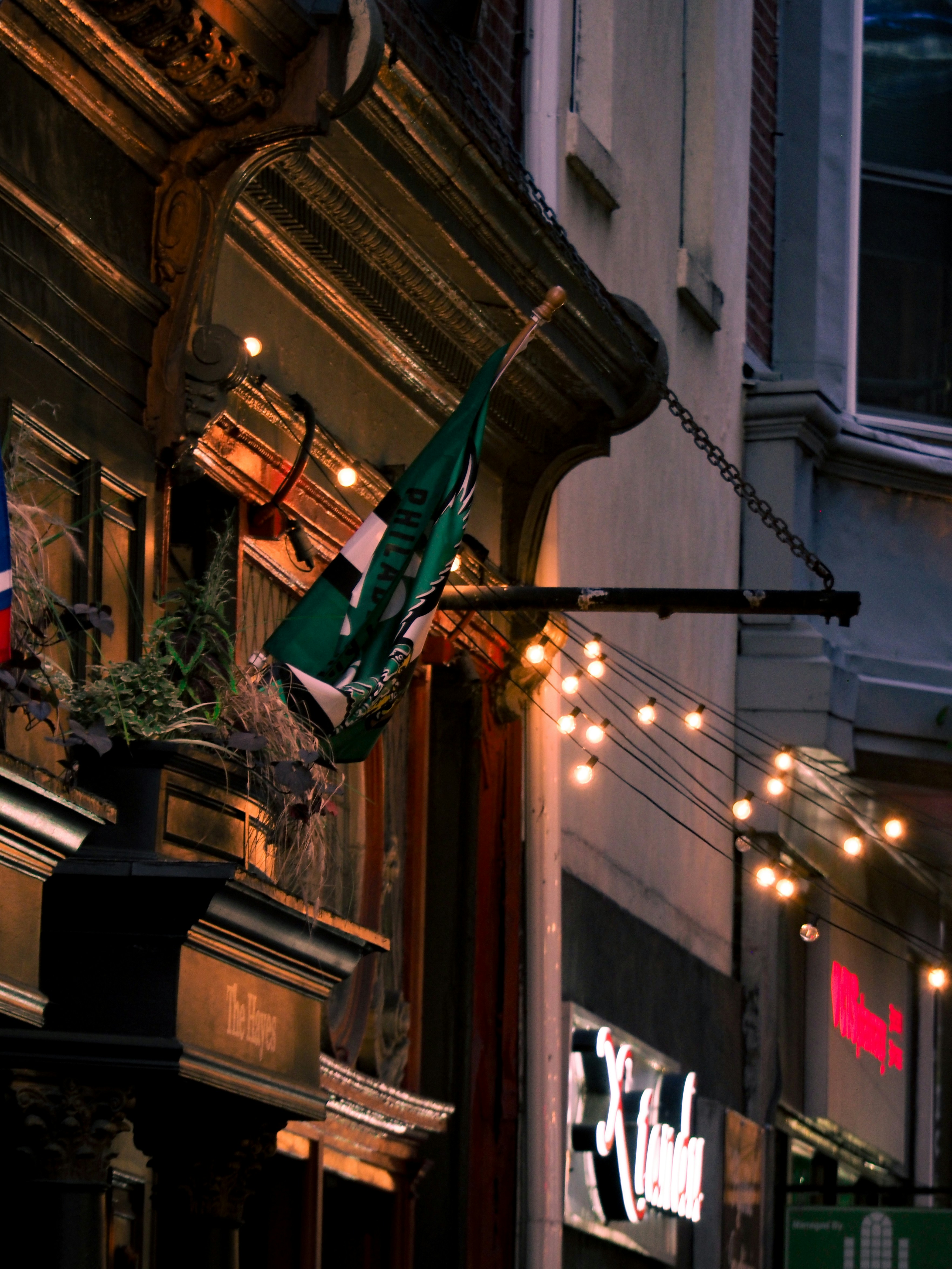 Green flag hangs outside building with string lights