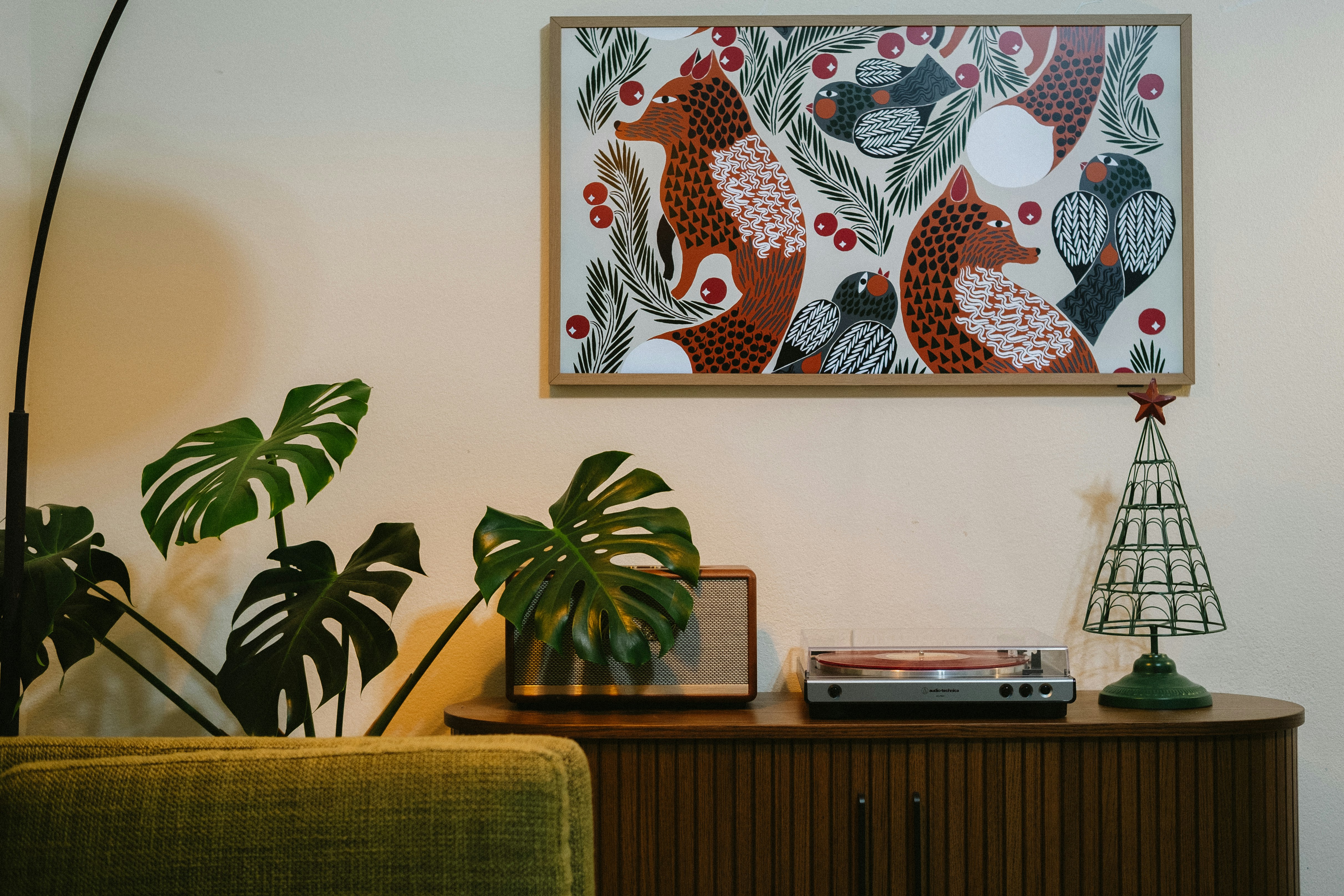 木製キャビネットの上にキツネや鳥が描かれた額装アート。