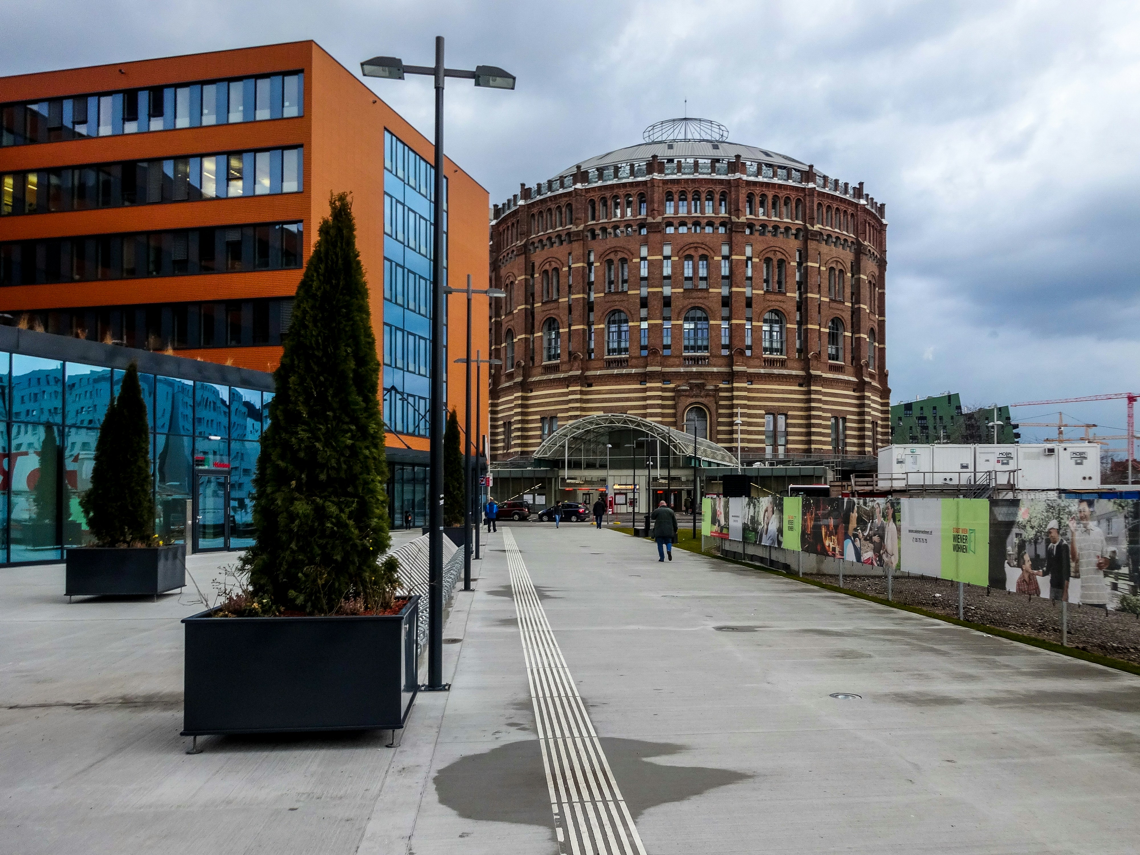 歴史的なレンガ造りのガソメーターの隣に近代的なオレンジ色の建物。