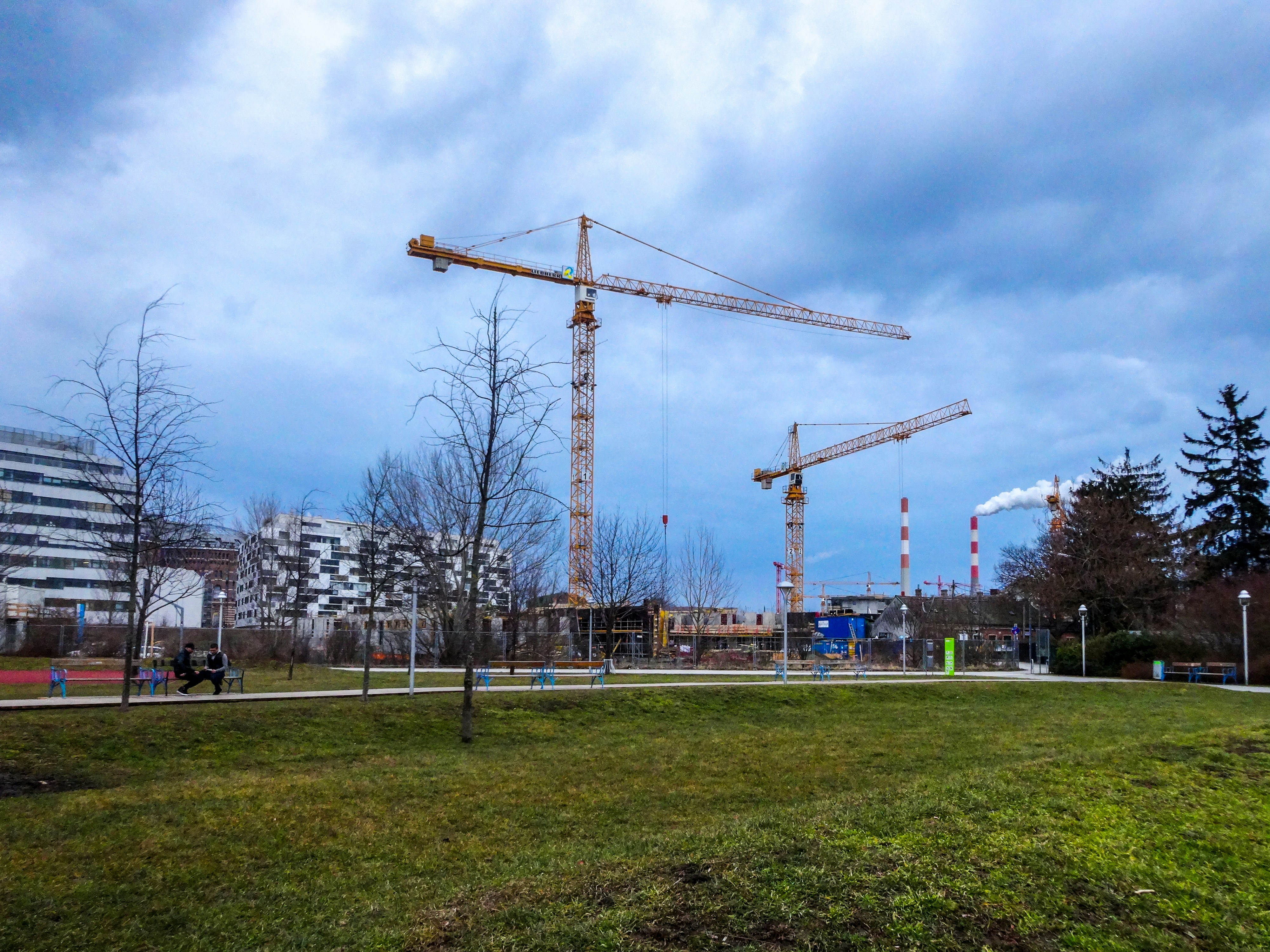 Construction cranes rise over a city landscape.