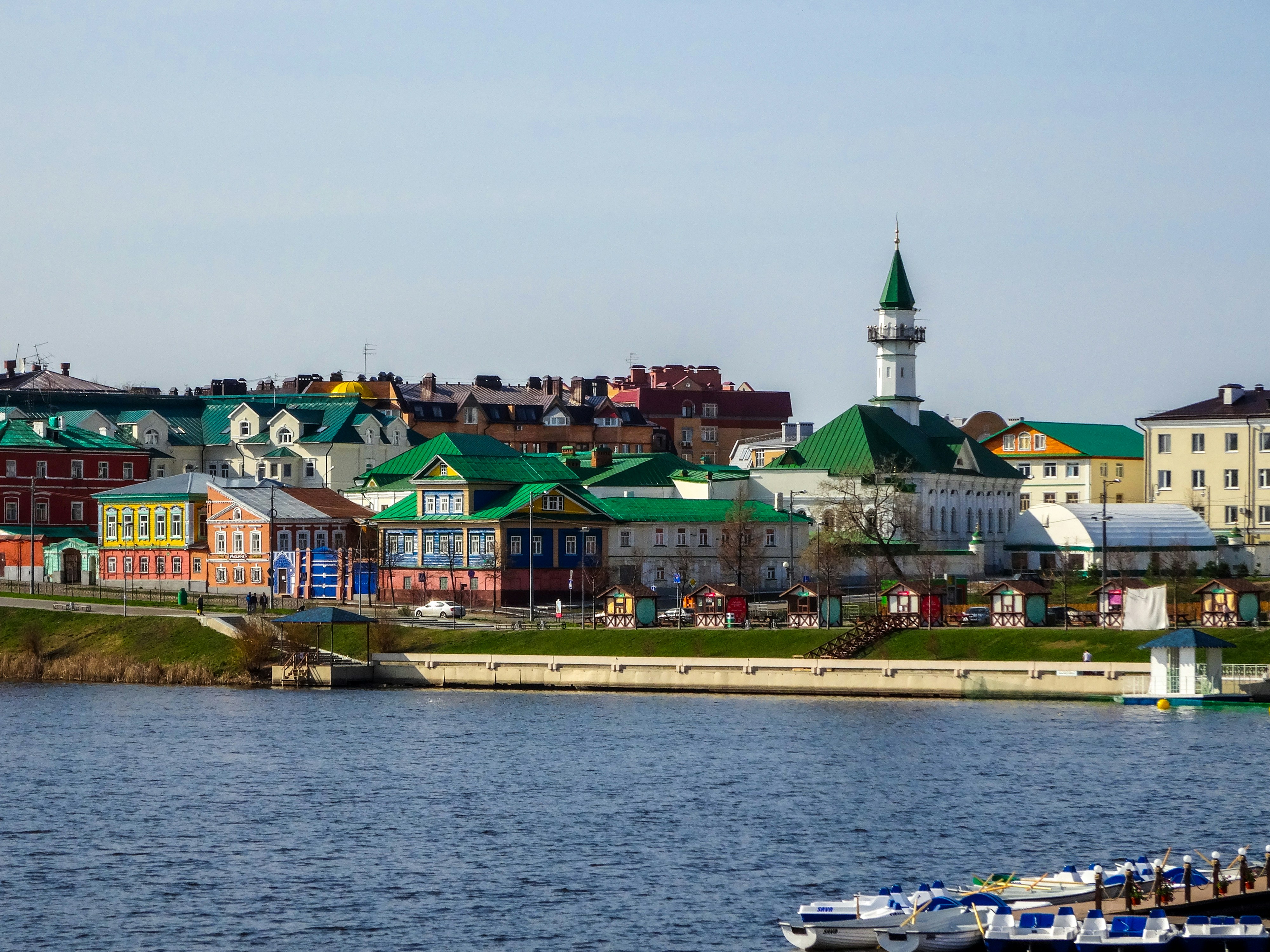 Colorful buildings line a riverbank with a mosque