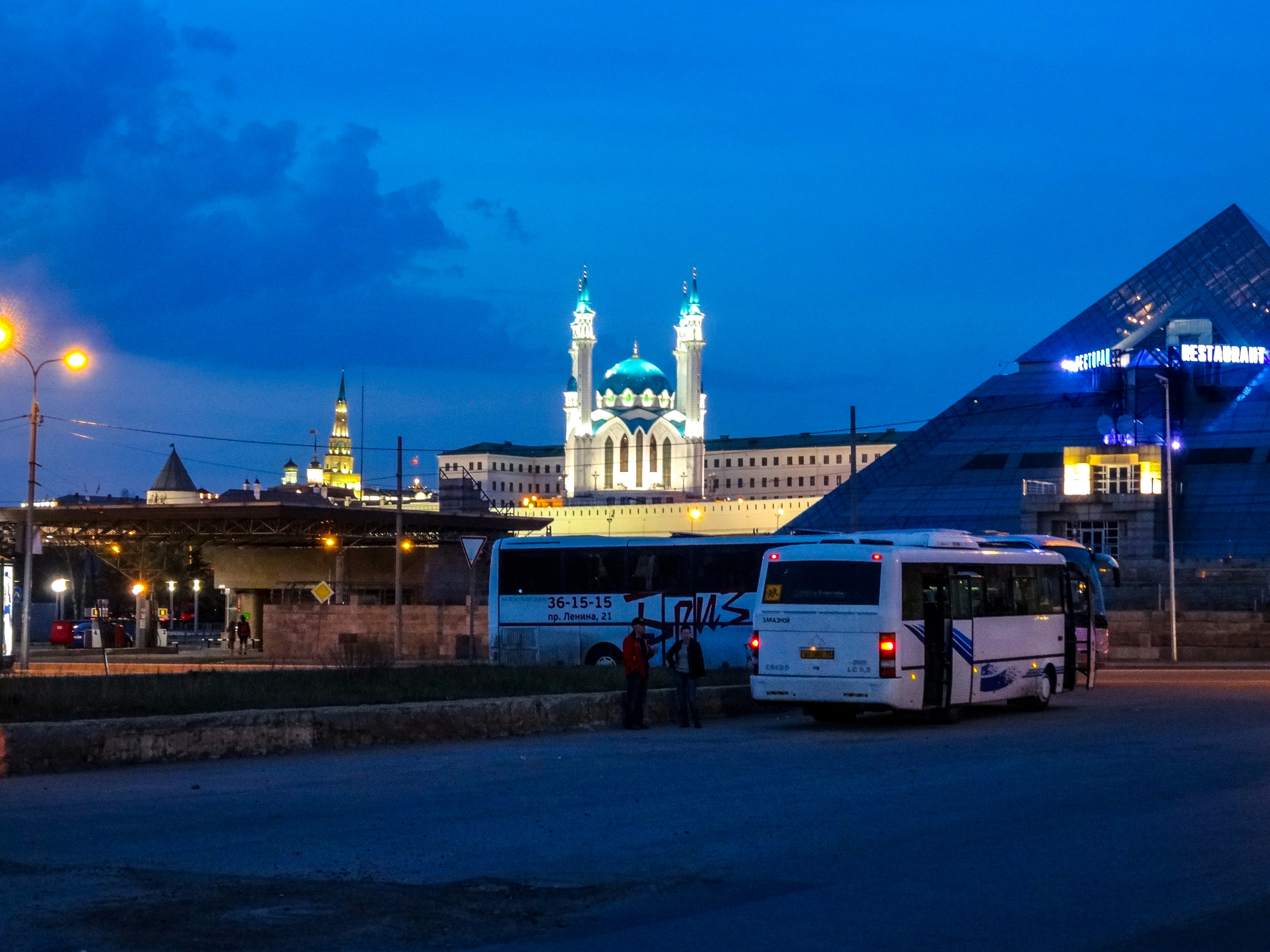 Buses parked near illuminated buildings at dusk