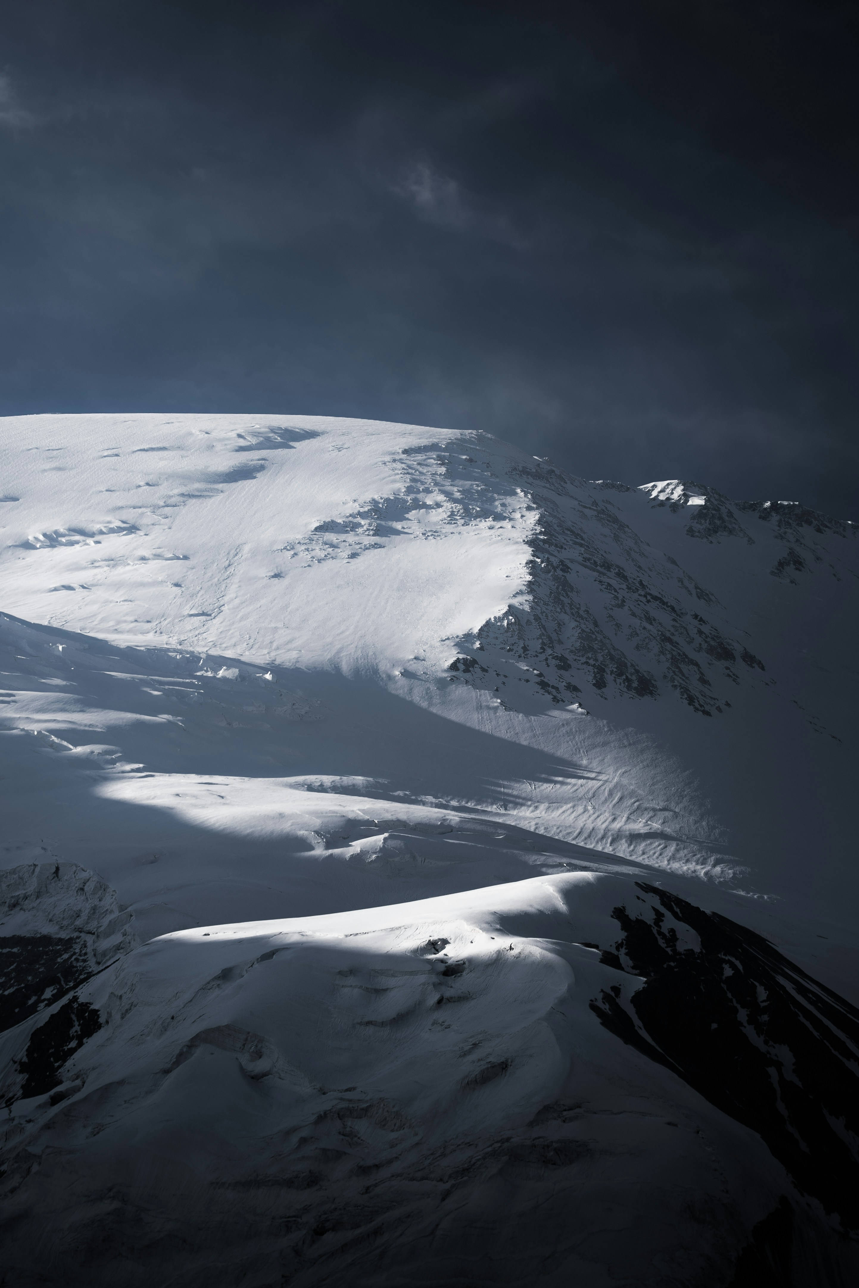 Snowy mountain range under dramatic dark clouds