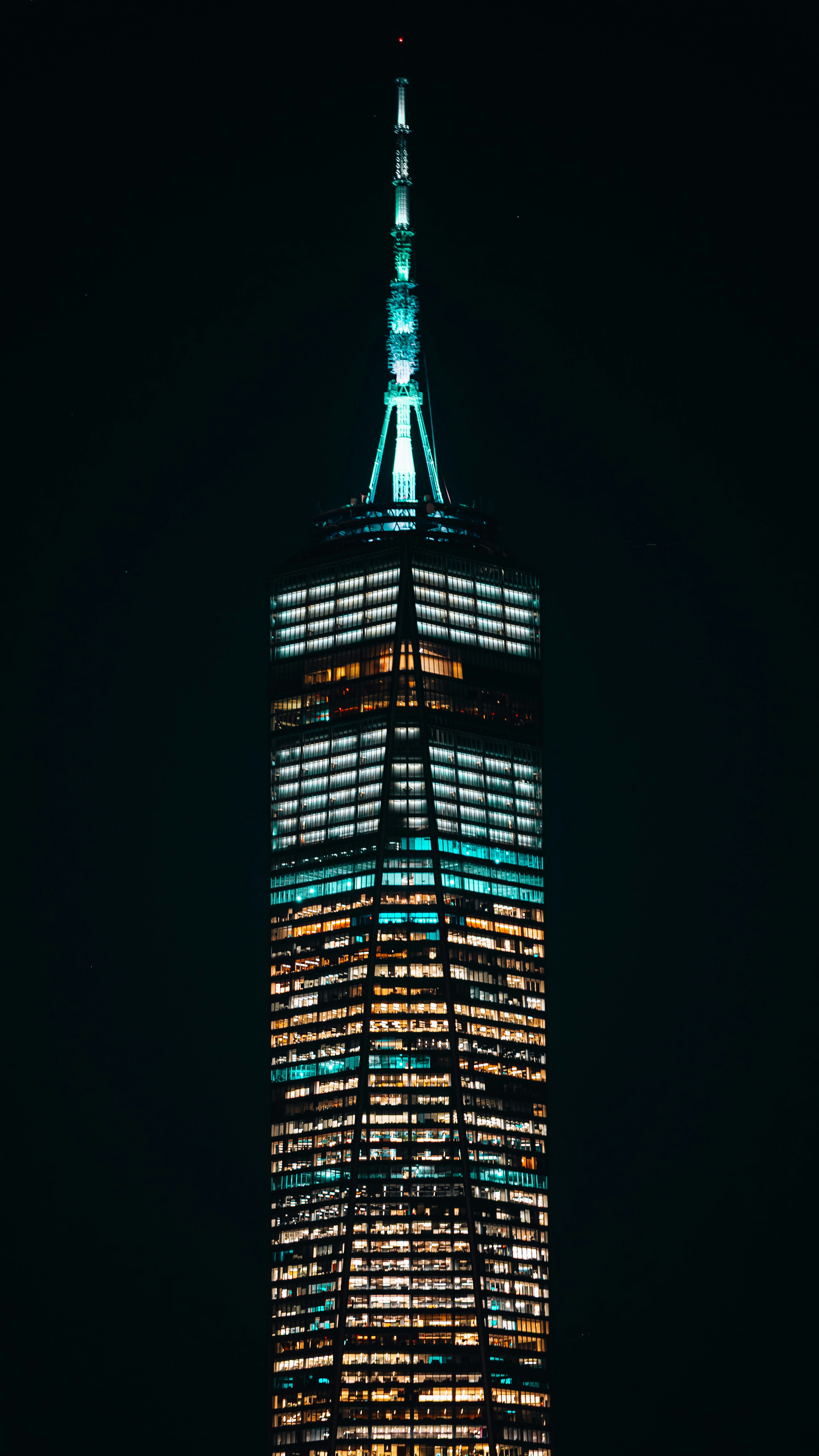 Un grattacielo alto illuminato di notte contro il cielo scuro.