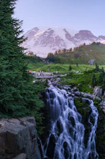 Waterfall cascading down rocks with snow-capped mountain background