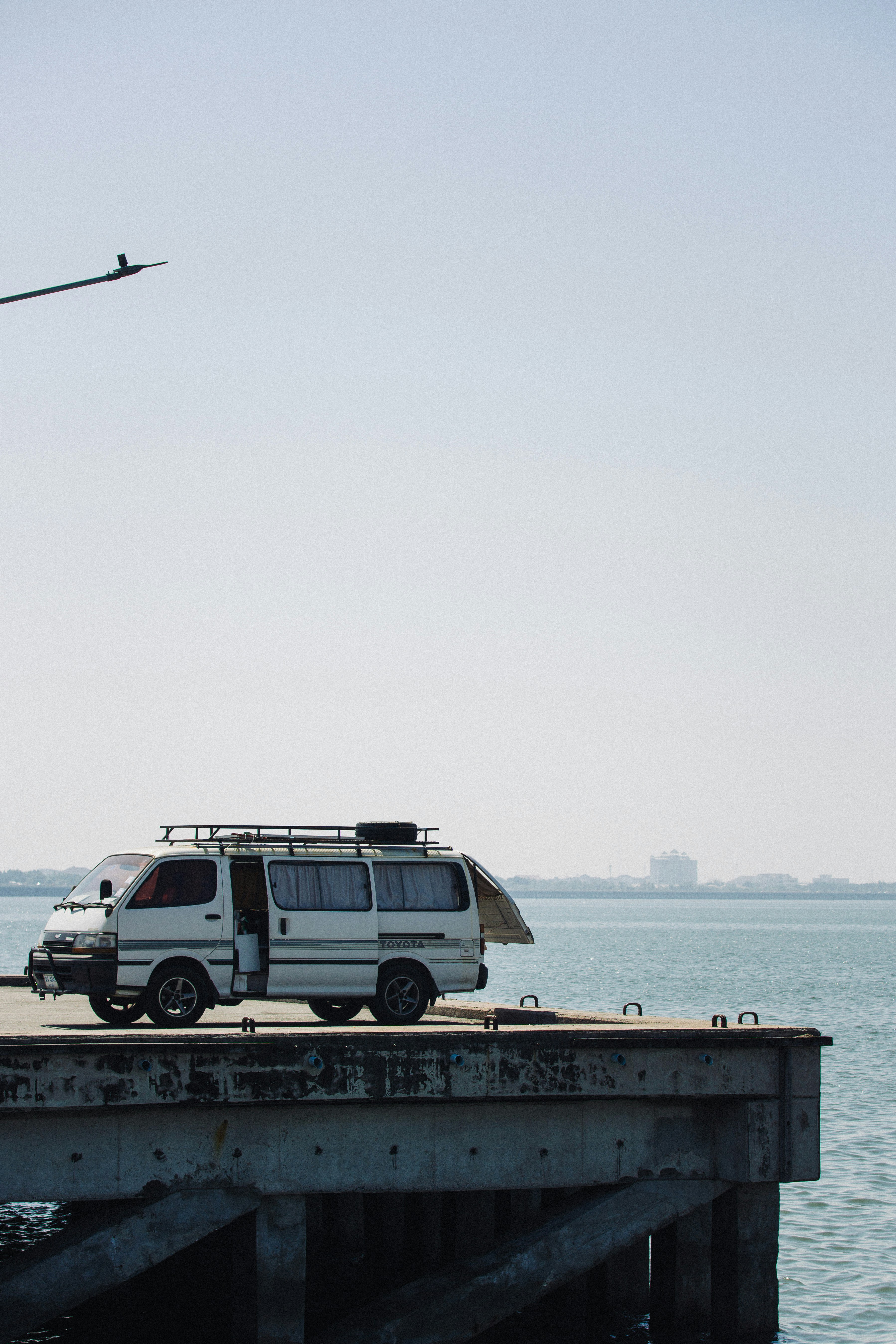 Weißer Wohnmobil auf einem Pier in Meeresnähe geparkt.