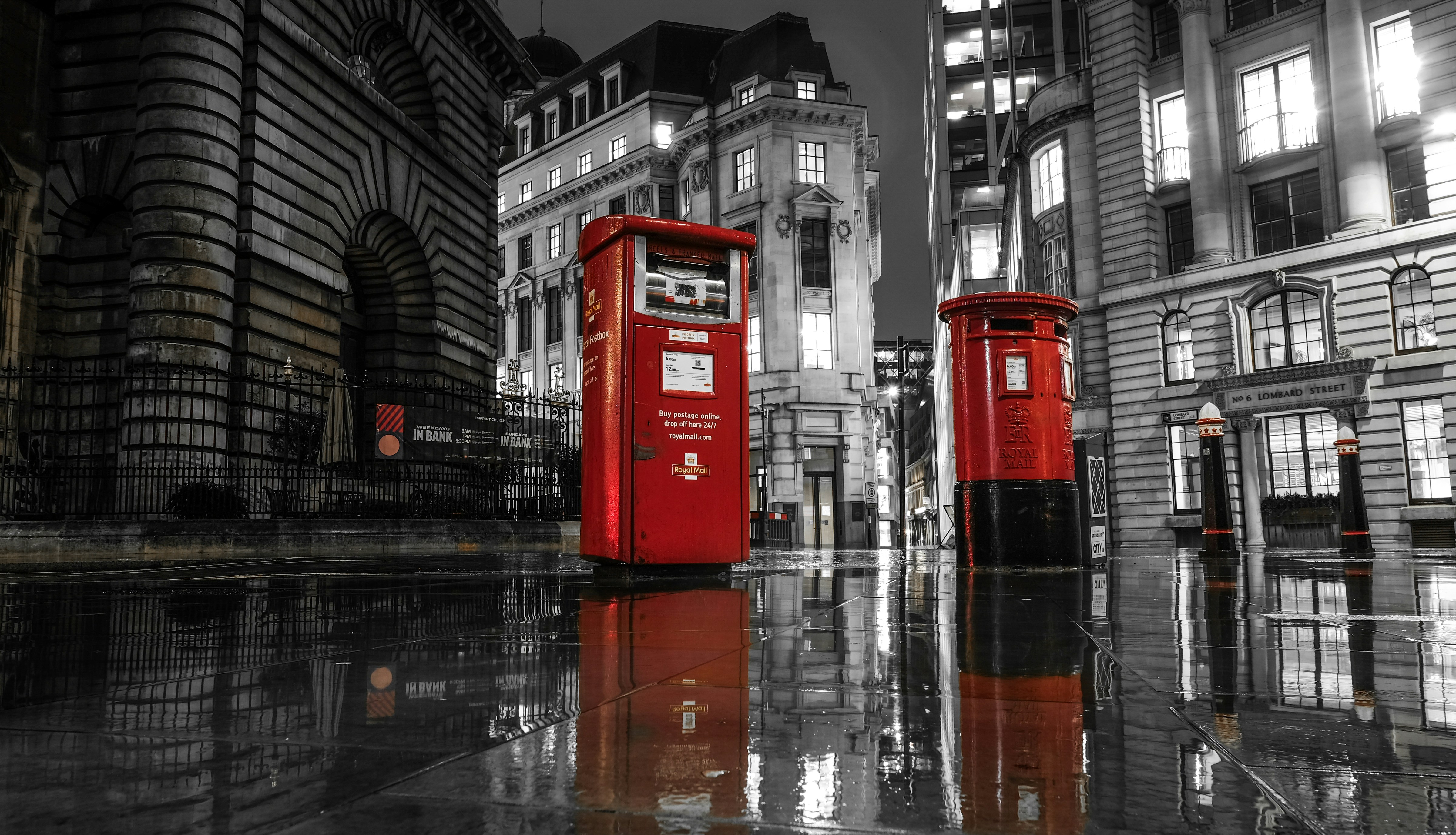 Red london post boxes on wet city street at night