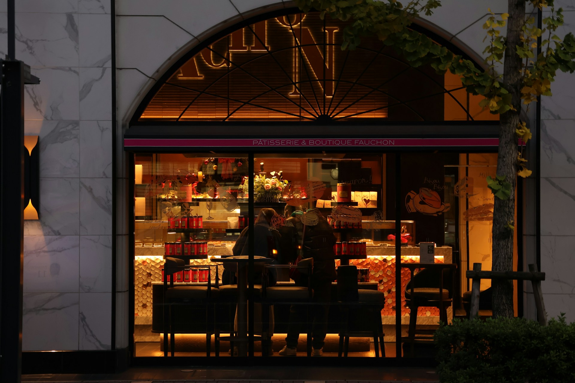 A brightly lit bakery storefront at dusk