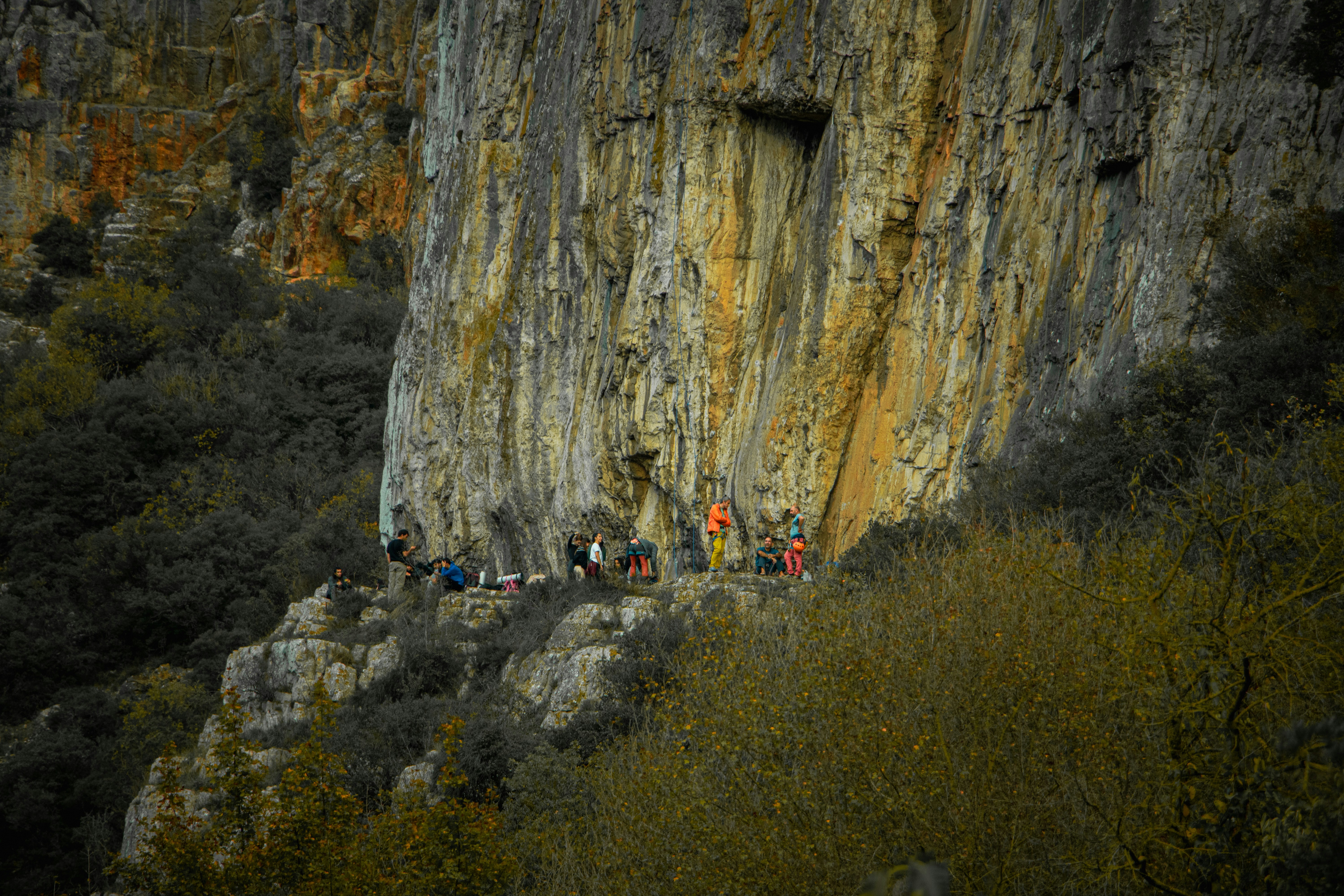 Climbers gathered at the base of a large rock face.