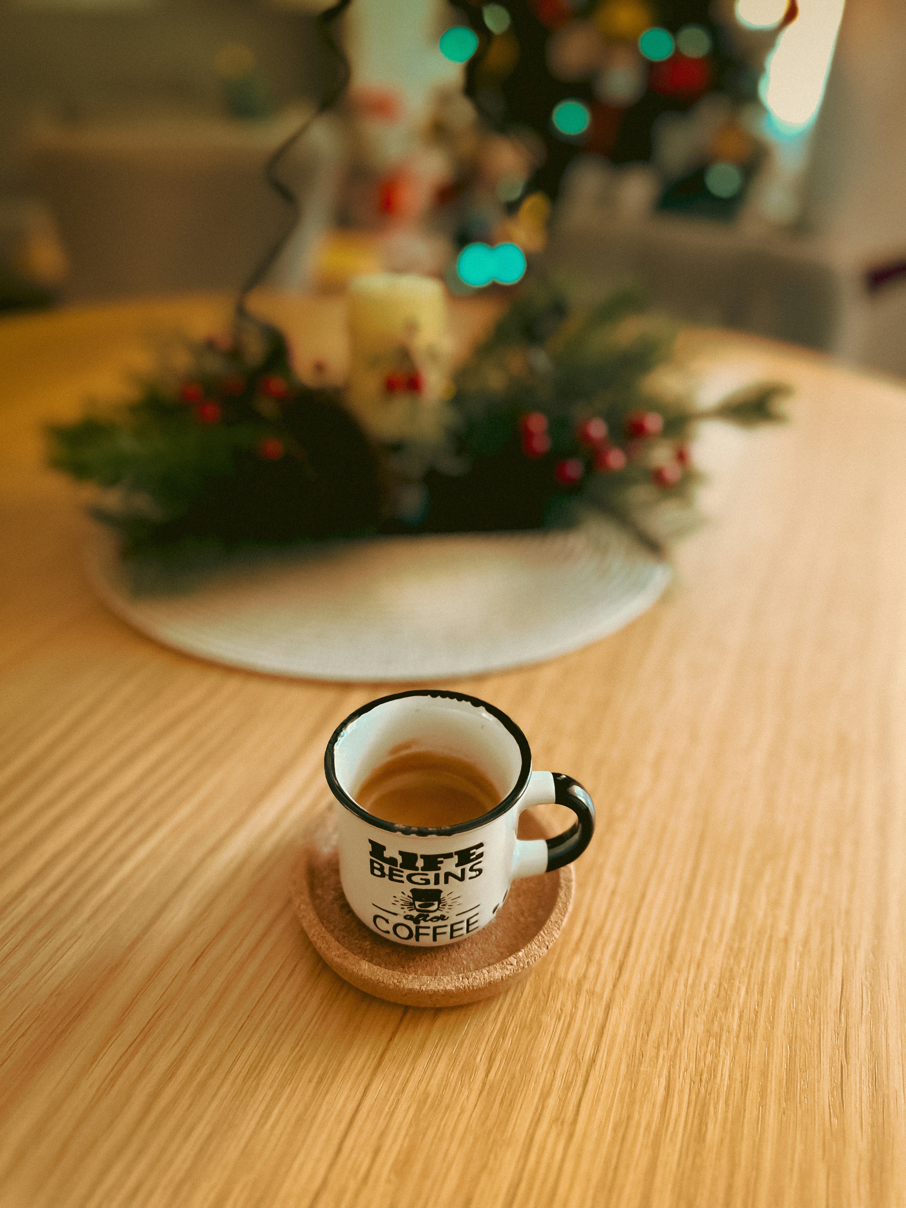 Espresso cup on a wooden table with festive decor.