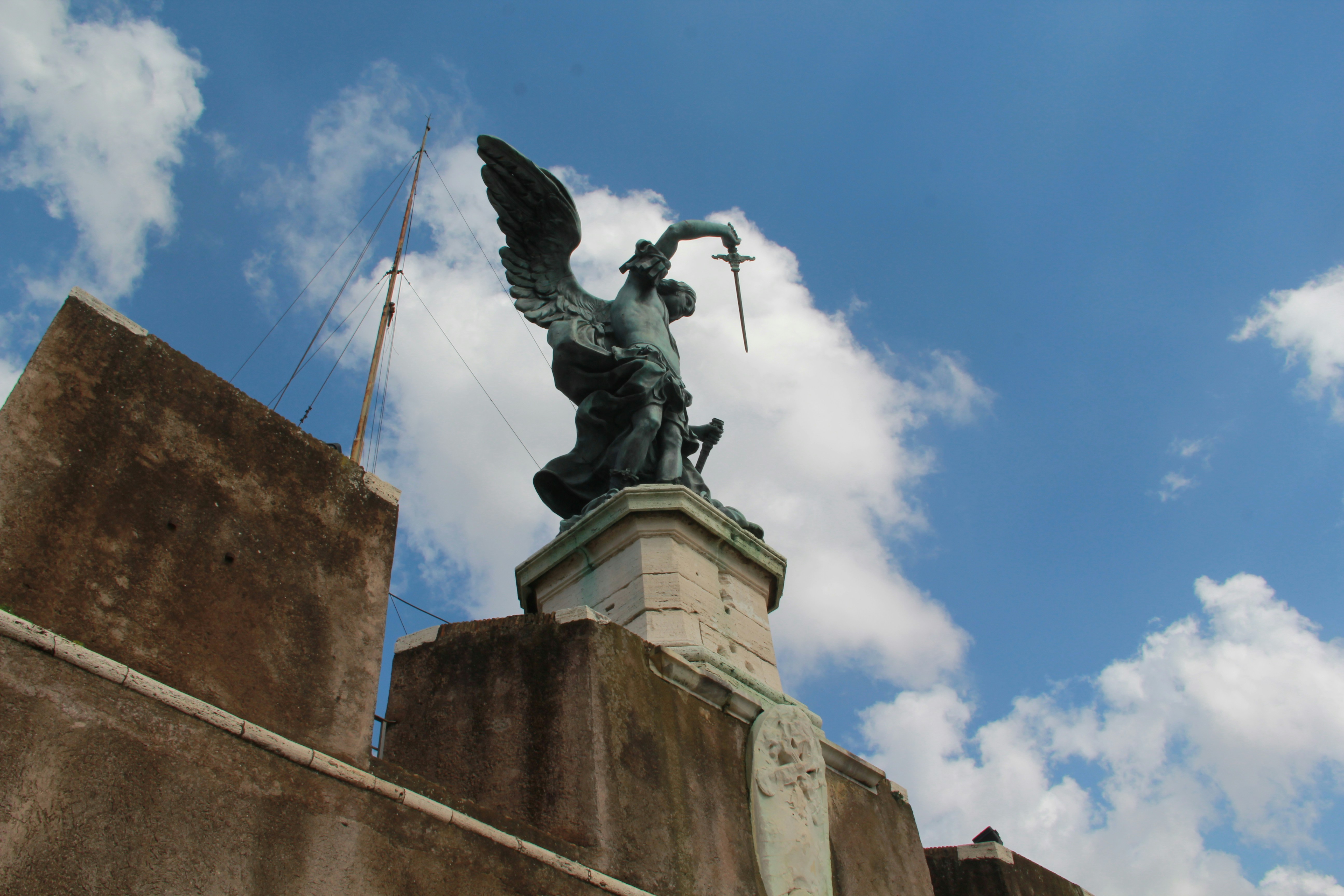 Angel statue on a stone wall under sky