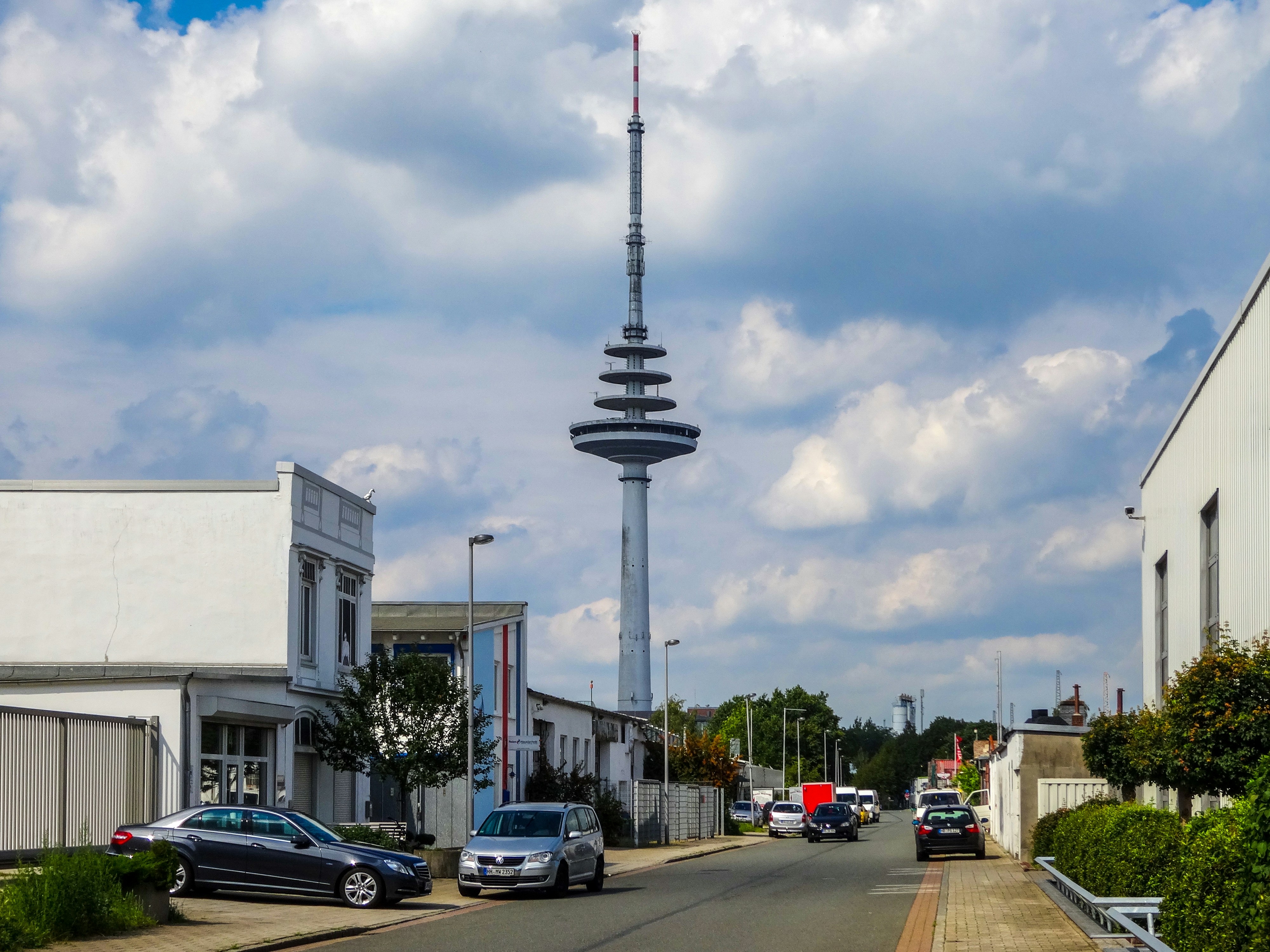 Tall broadcasting tower stands over suburban street.