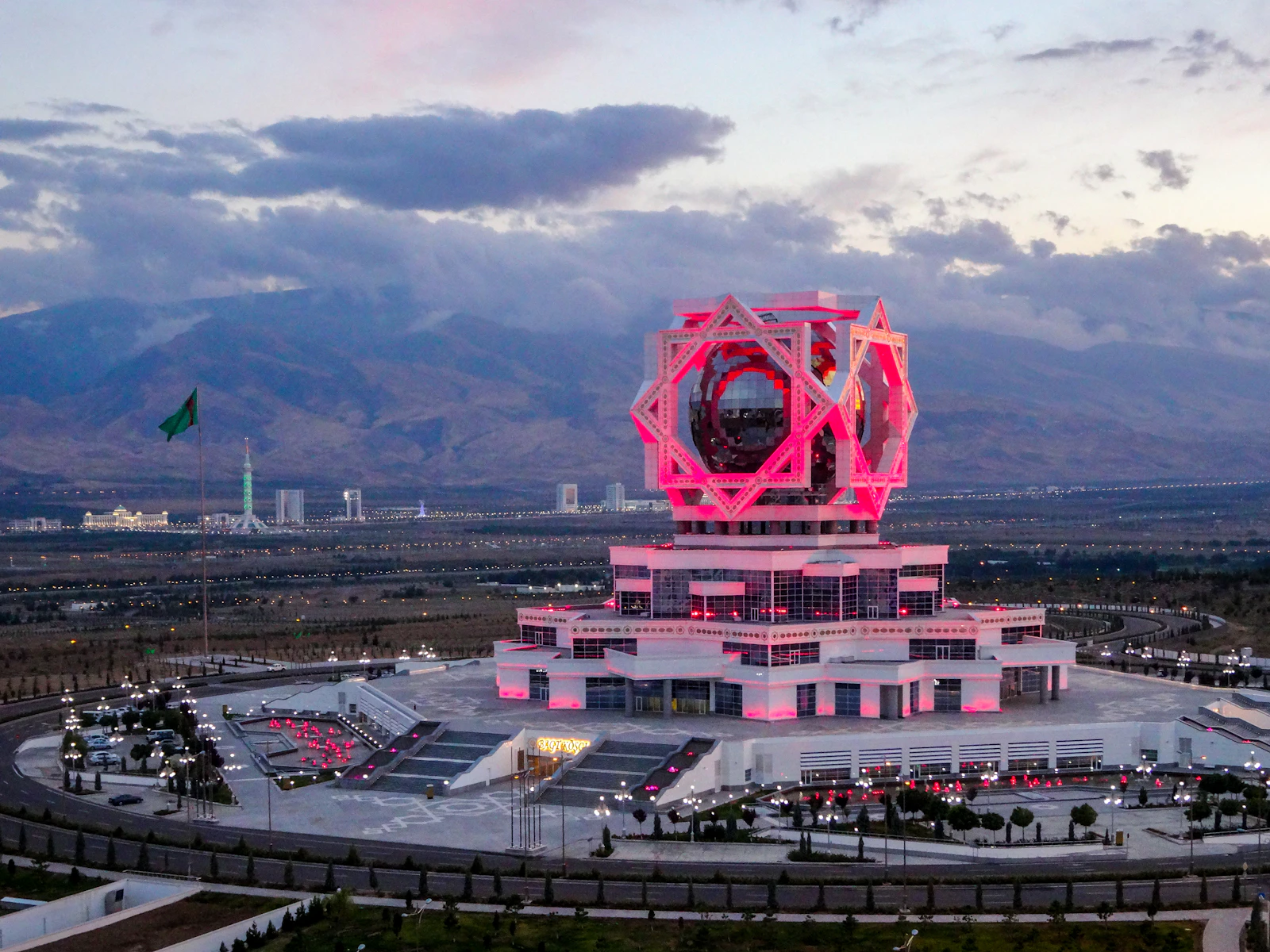 The Wedding Palace in Ashgabat lit at dusk, the marble city behind it