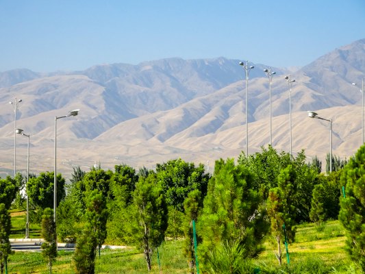 Green trees with distant mountains under a clear sky — Ashgabat, Turkmenistan