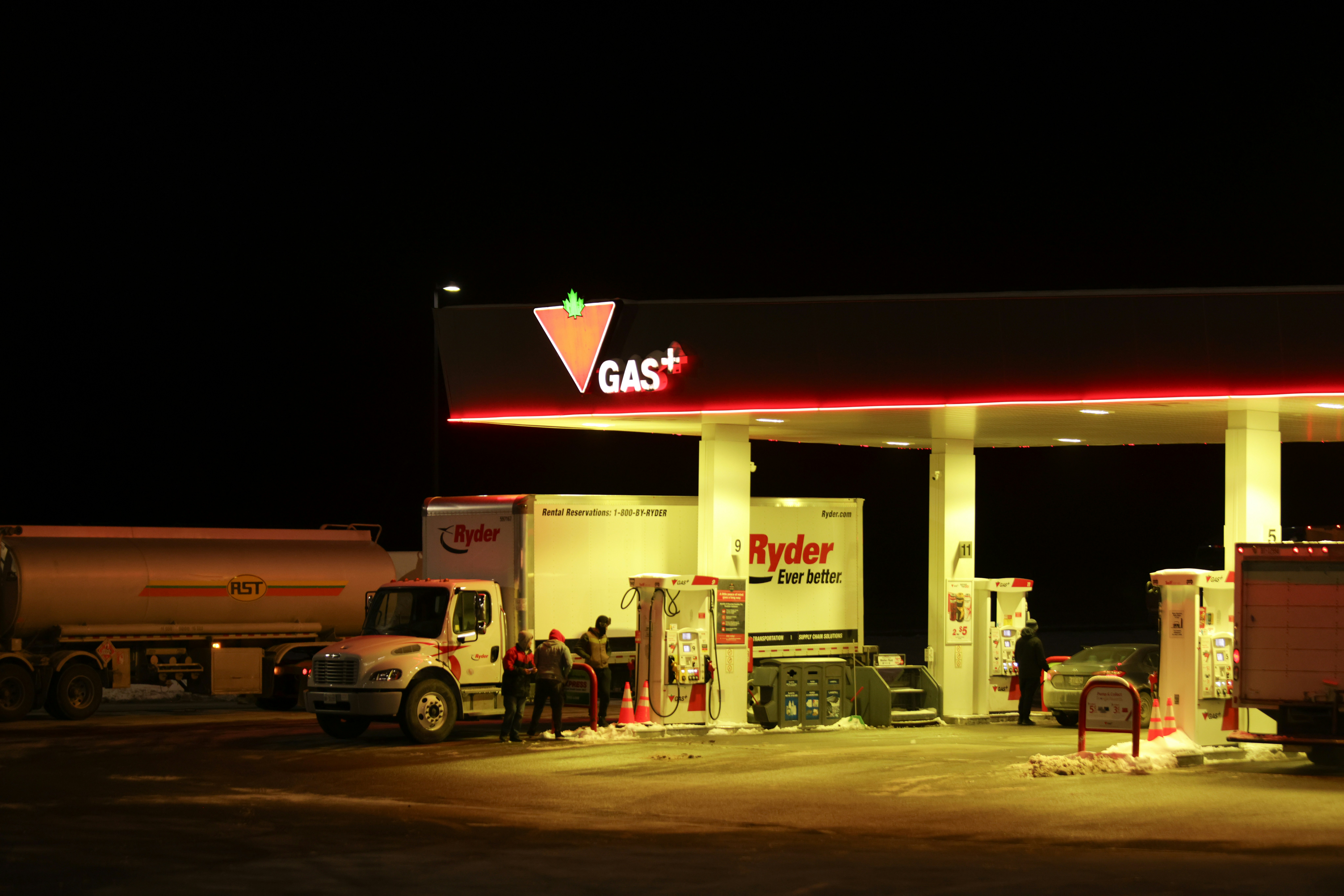 Gas station at night with trucks and cars.