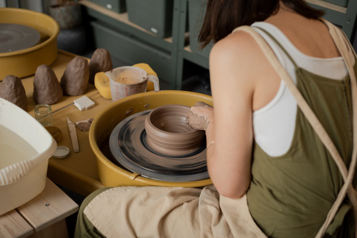 A woman shaping clay on a pottery wheel