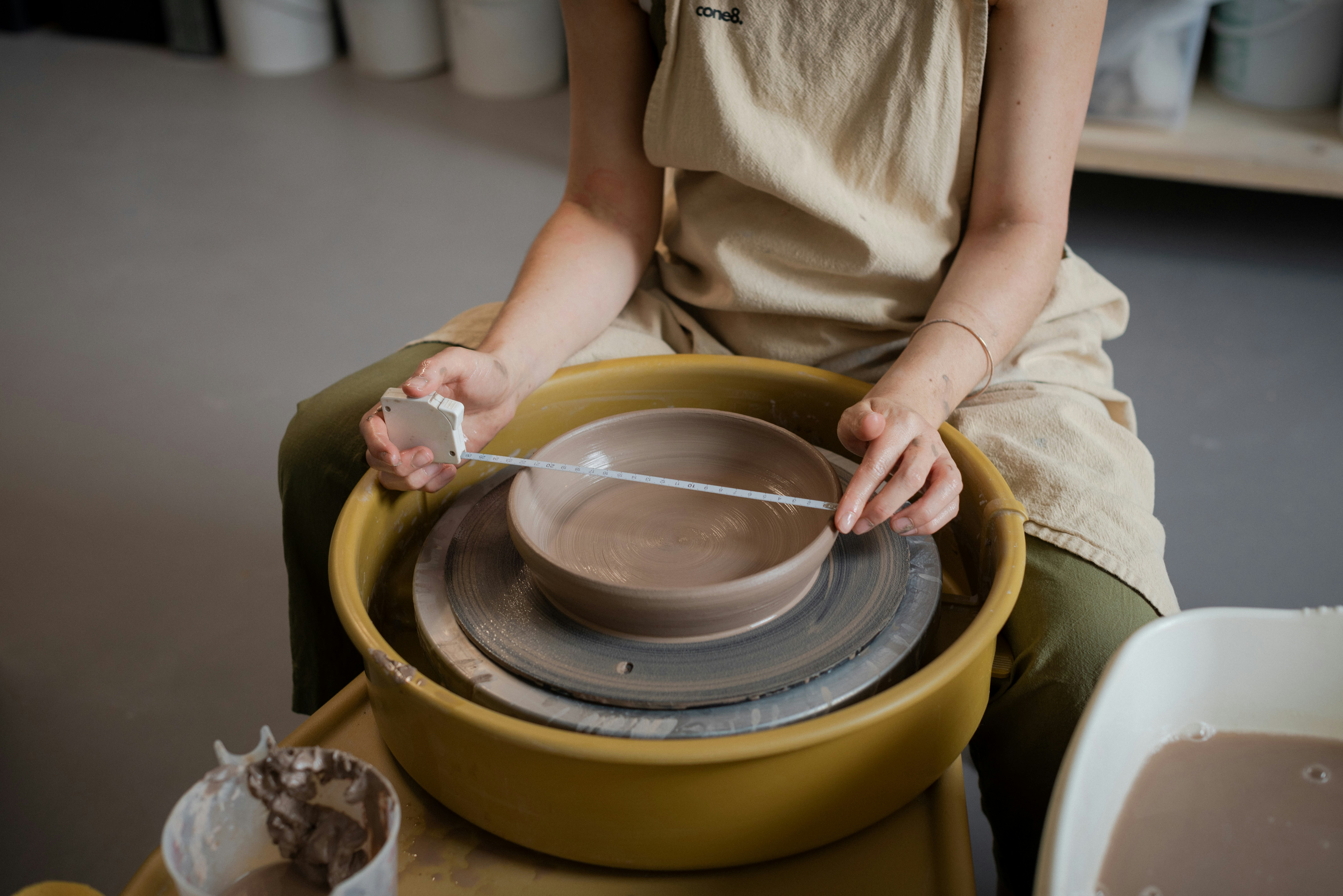 Person shaping clay on a pottery wheel