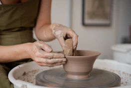 Hands shaping clay on a pottery wheel