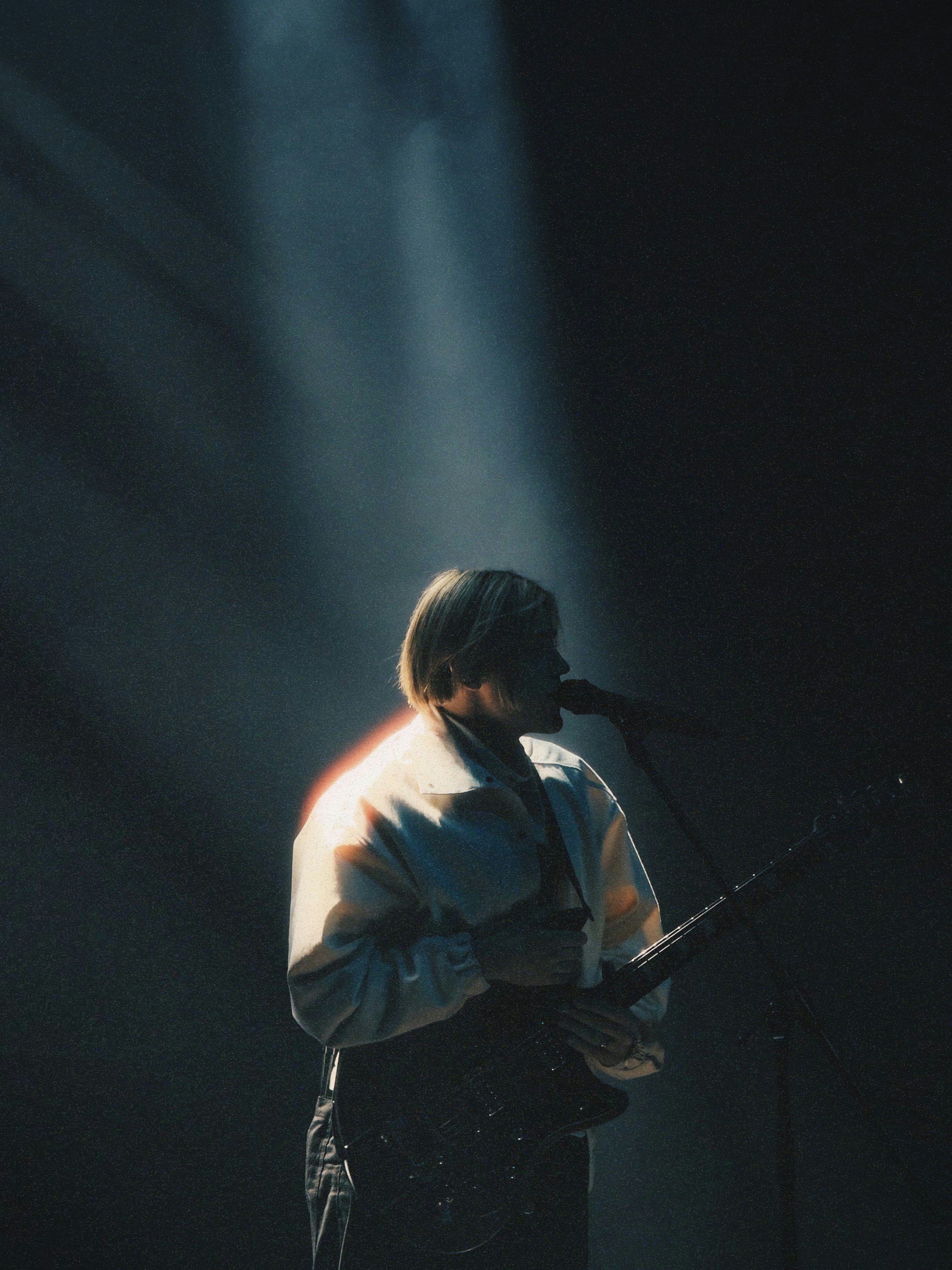 Musician plays guitar and sings on stage.