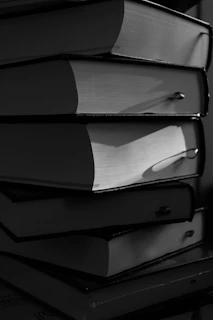 A stack of thick, hardcover books in black and white.
