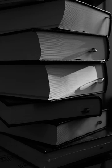 A stack of thick, hardcover books in black and white.