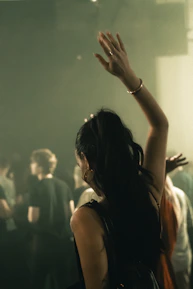Woman dancing with arm raised at a concert.