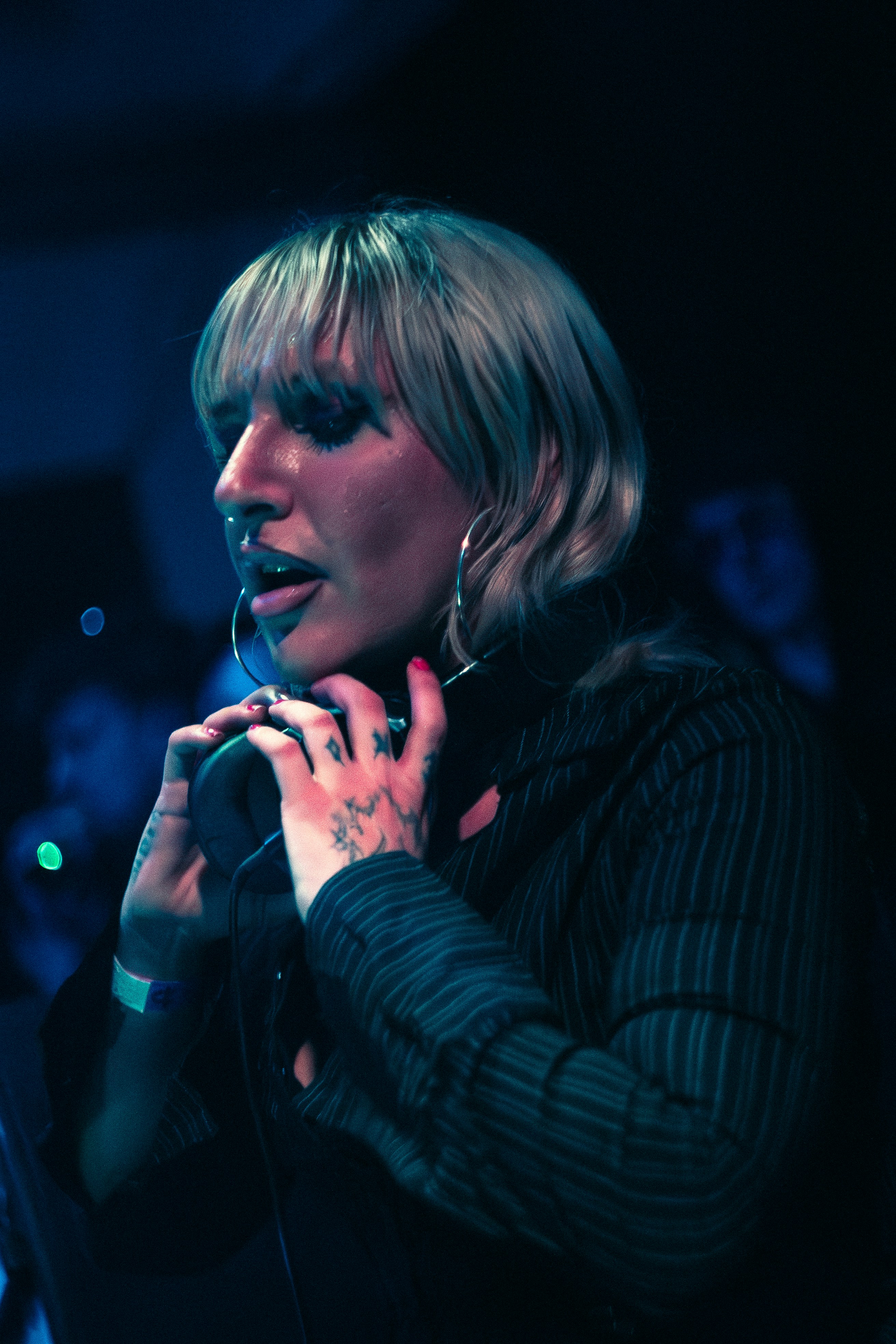 Frau mit blonden Haaren und Tattoos, die auf der Bühne singt.