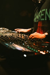 Dj mixing music on a soundboard with hands.
